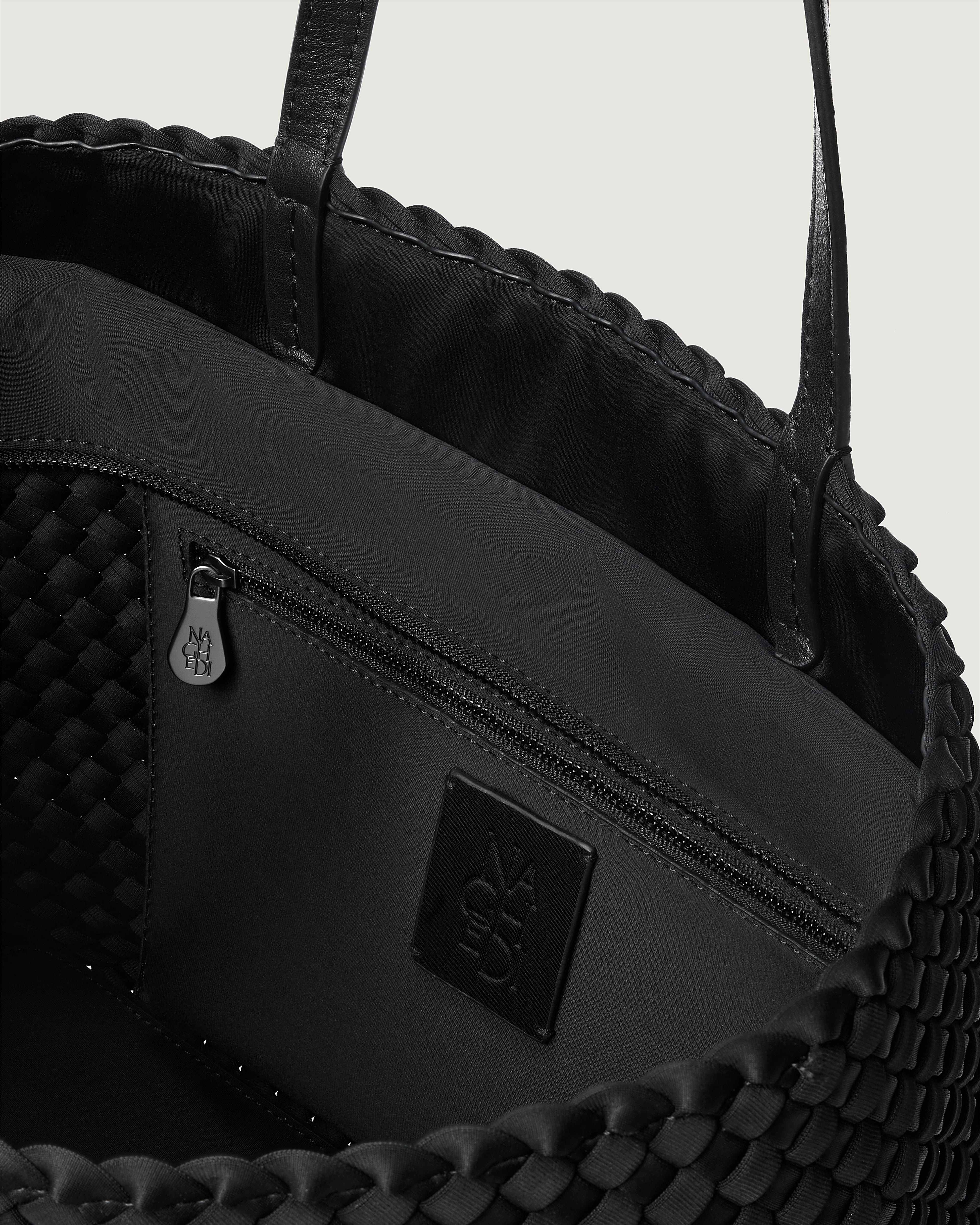 Interior close-up of Jetsetter Tote in Onyx showing its top zip closure, interior pocket, and unlined interior.