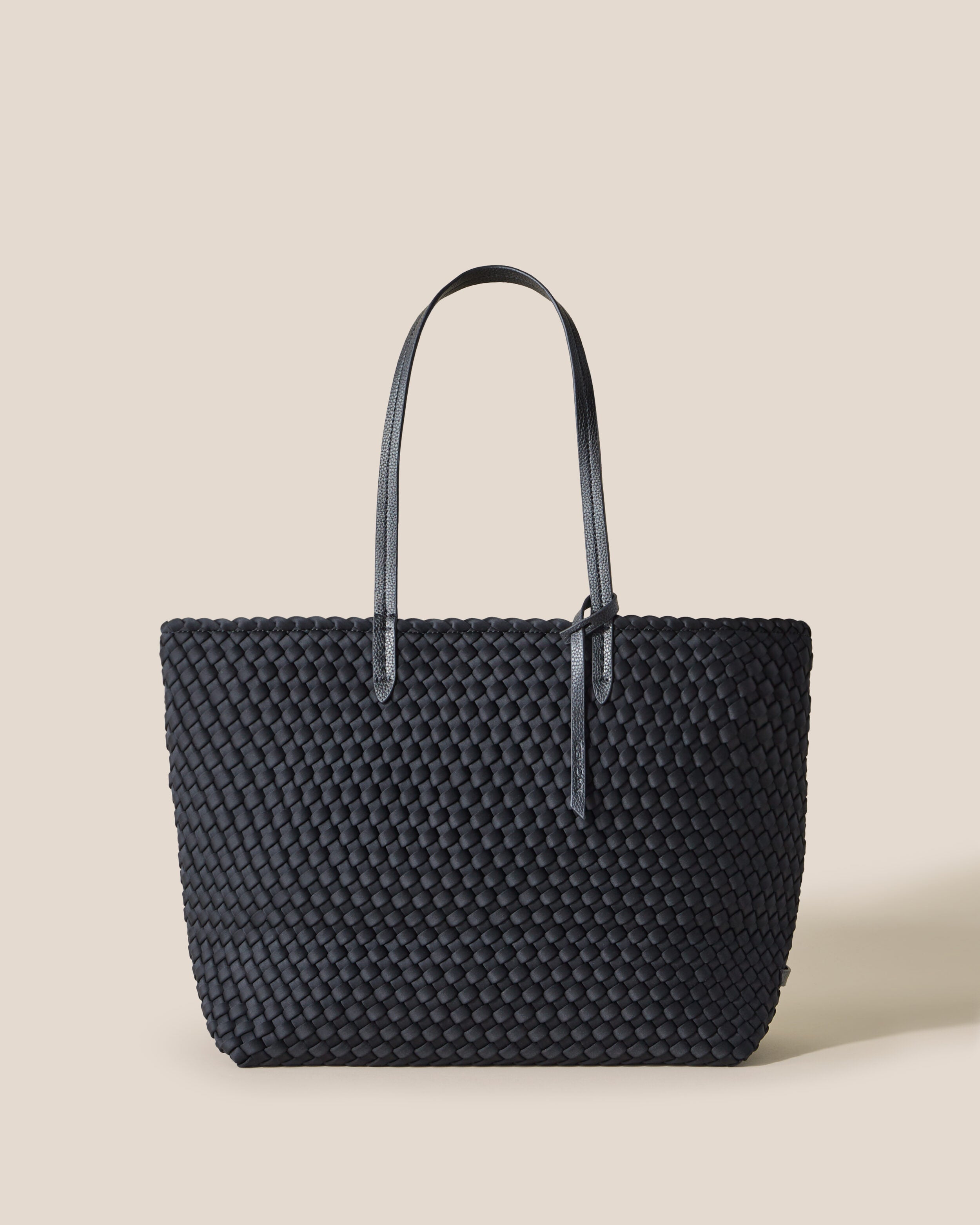 Jetsetter Tote in Onyx, a true black tone, in handwoven neoprene, featuring a top zip closure, and vegan leather handles.