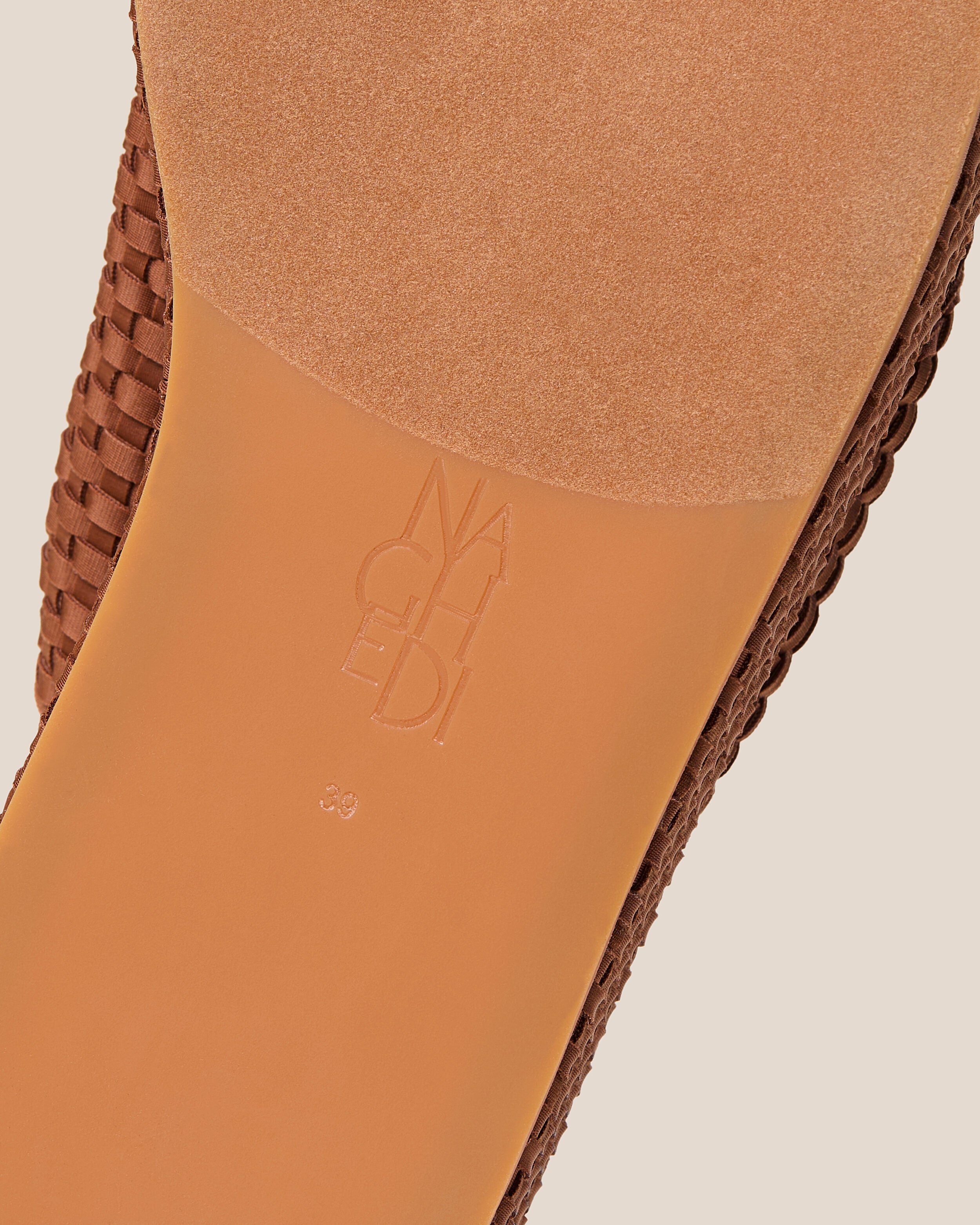 Shoe sole showing natural rubber sole, stamped NAGHEDI logo and size detail for The Laguna Platform in Adobe.