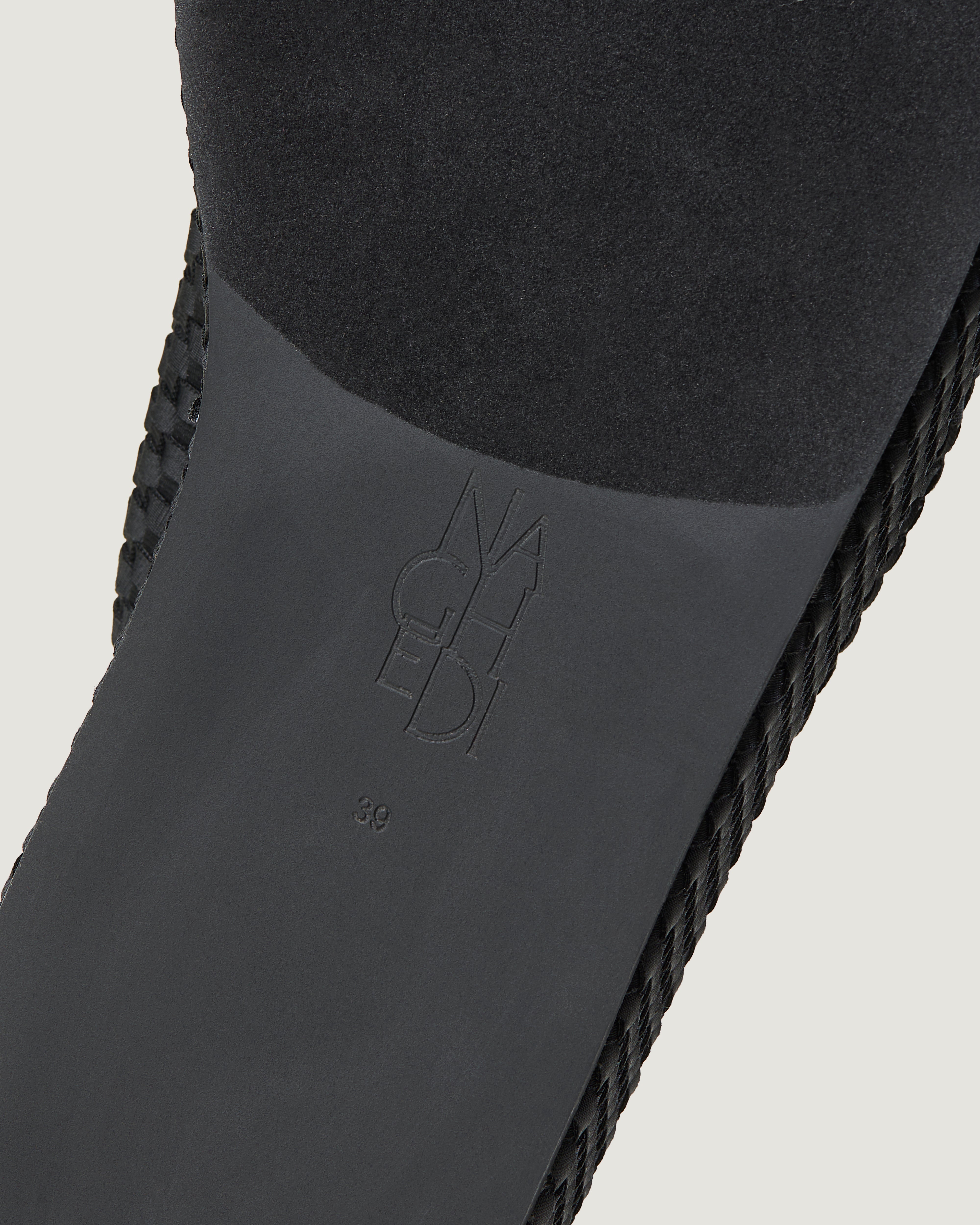 Shoe sole showing natural rubber sole, stamped NAGHEDI logo and size detail for The Laguna Platform in Onyx.