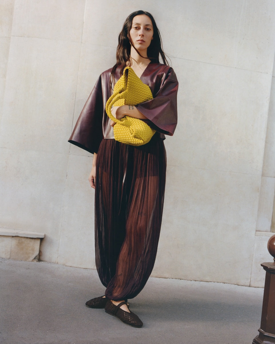 Full body on model image of the St. Barths Medium Tote in Ochre. Highlighting the handwoven neoprene design and top handles.