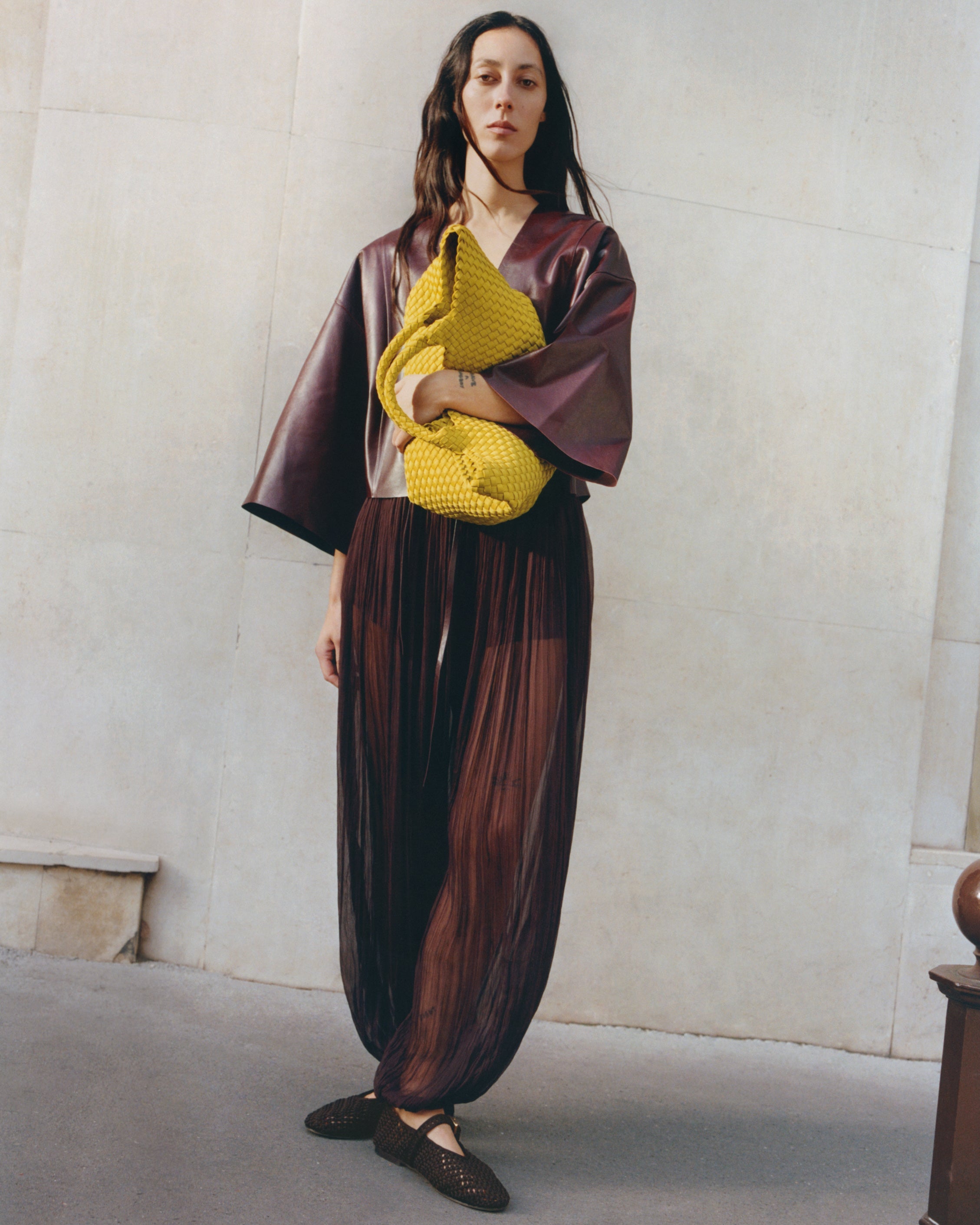 Full body on model image of the St. Barths Medium Tote in Ochre. Highlighting the handwoven neoprene design and top handles.