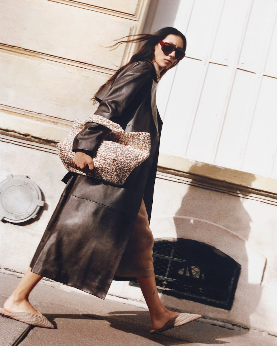 Full body on model image of the St. Barths Medium Tote in Flax. Highlighting the handwoven neoprene design and top handles.