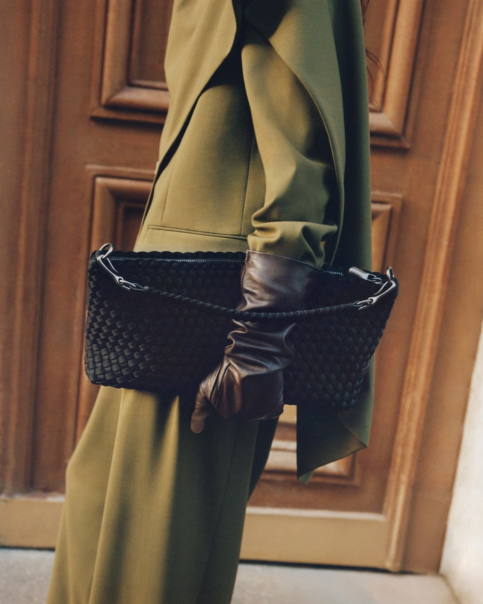 On model close-up of Porto Half-Moon in Onyx showing its hand stitched strap and handwoven neoprene design.