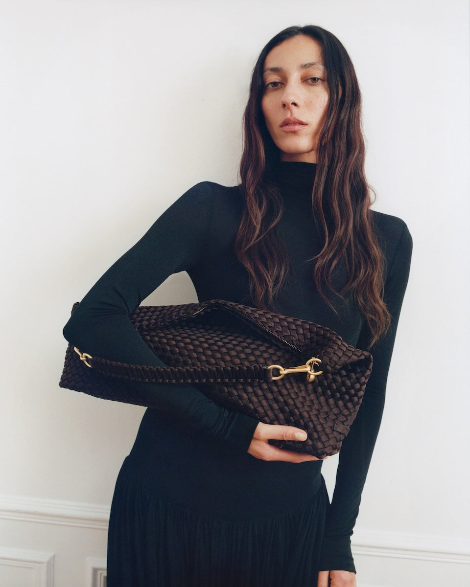 On model close-up of Porto Half-Moon in Chocolate showing its hand stitched strap and custom brushed gold 