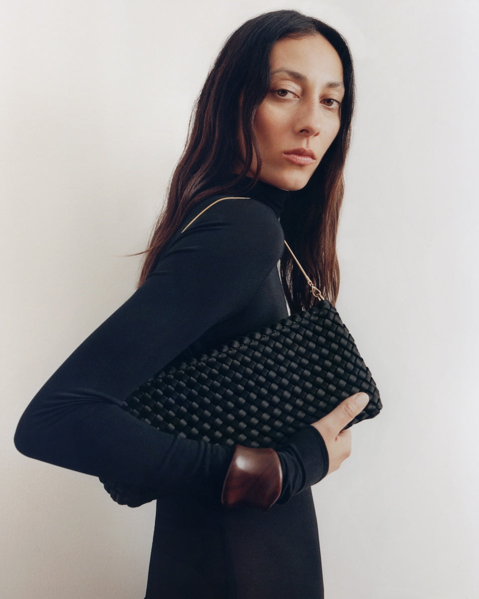 On model close up of the Gala Clutch in Onyx. Highlighting the handwoven satin and the removable gold chain.