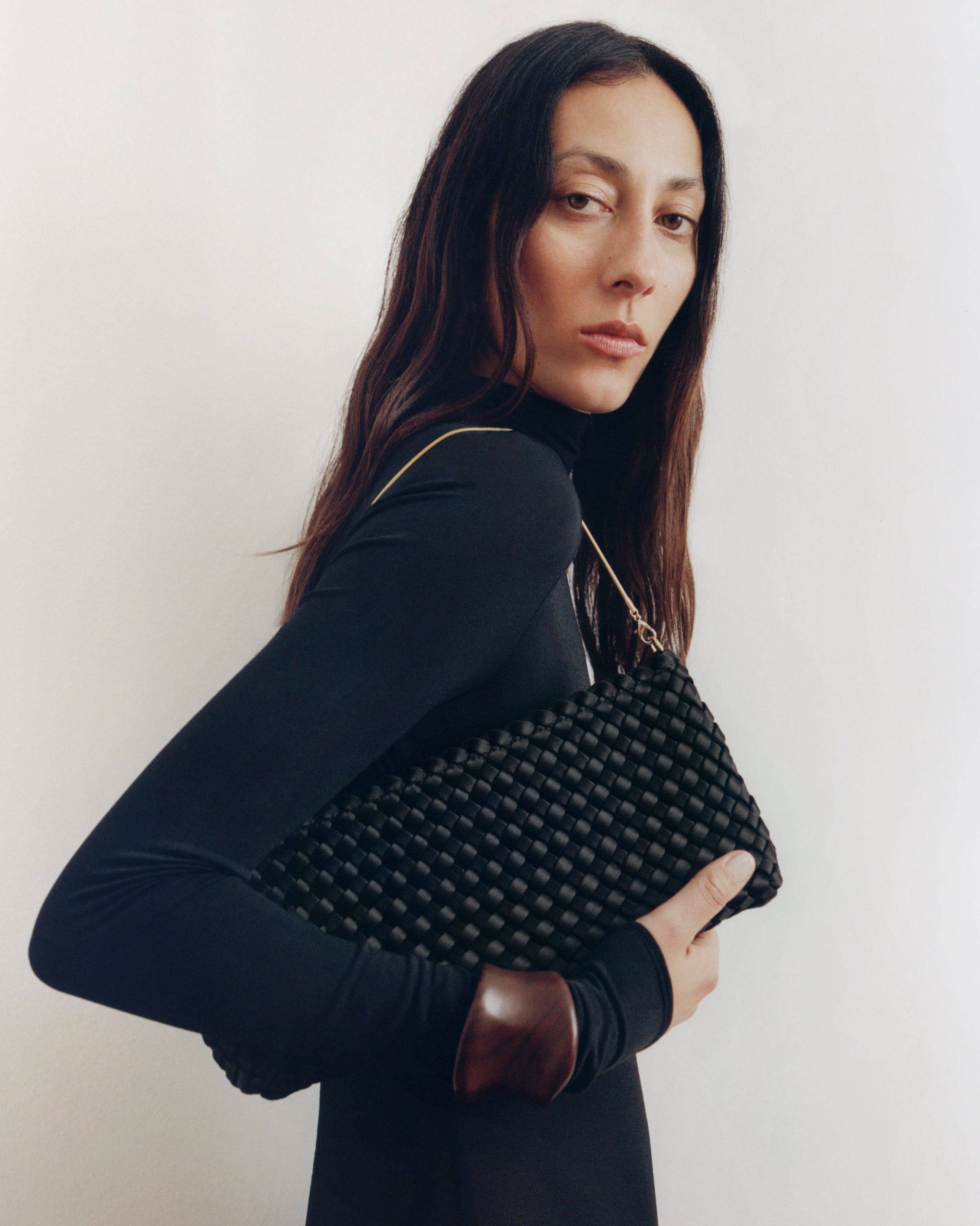 On model close up of the Gala Clutch in Onyx. Highlighting the handwoven satin and the removable gold chain.