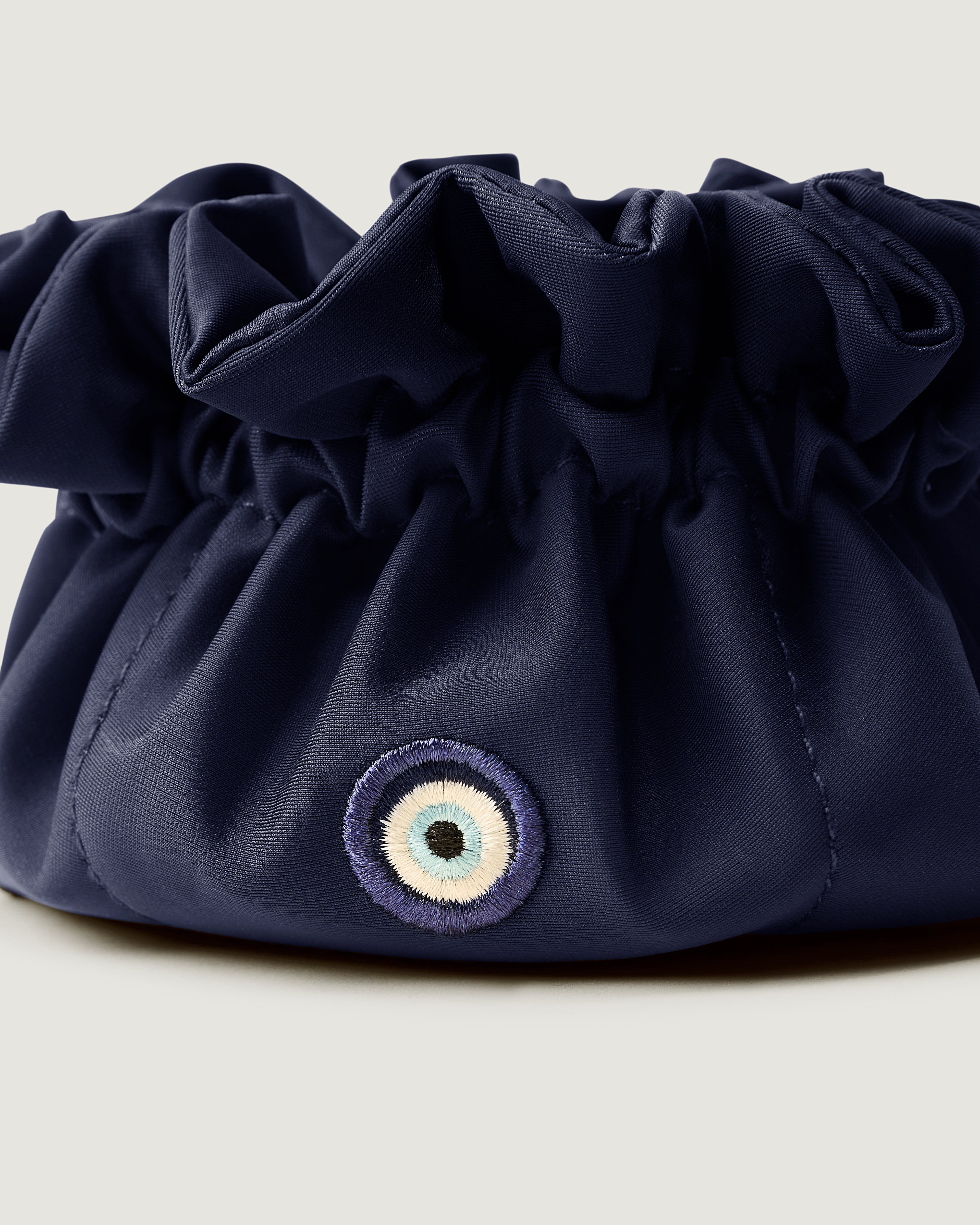 Close up of Lotus Jewelry Pouch in Ink Blue highlighting the Evil Eye embroidery.