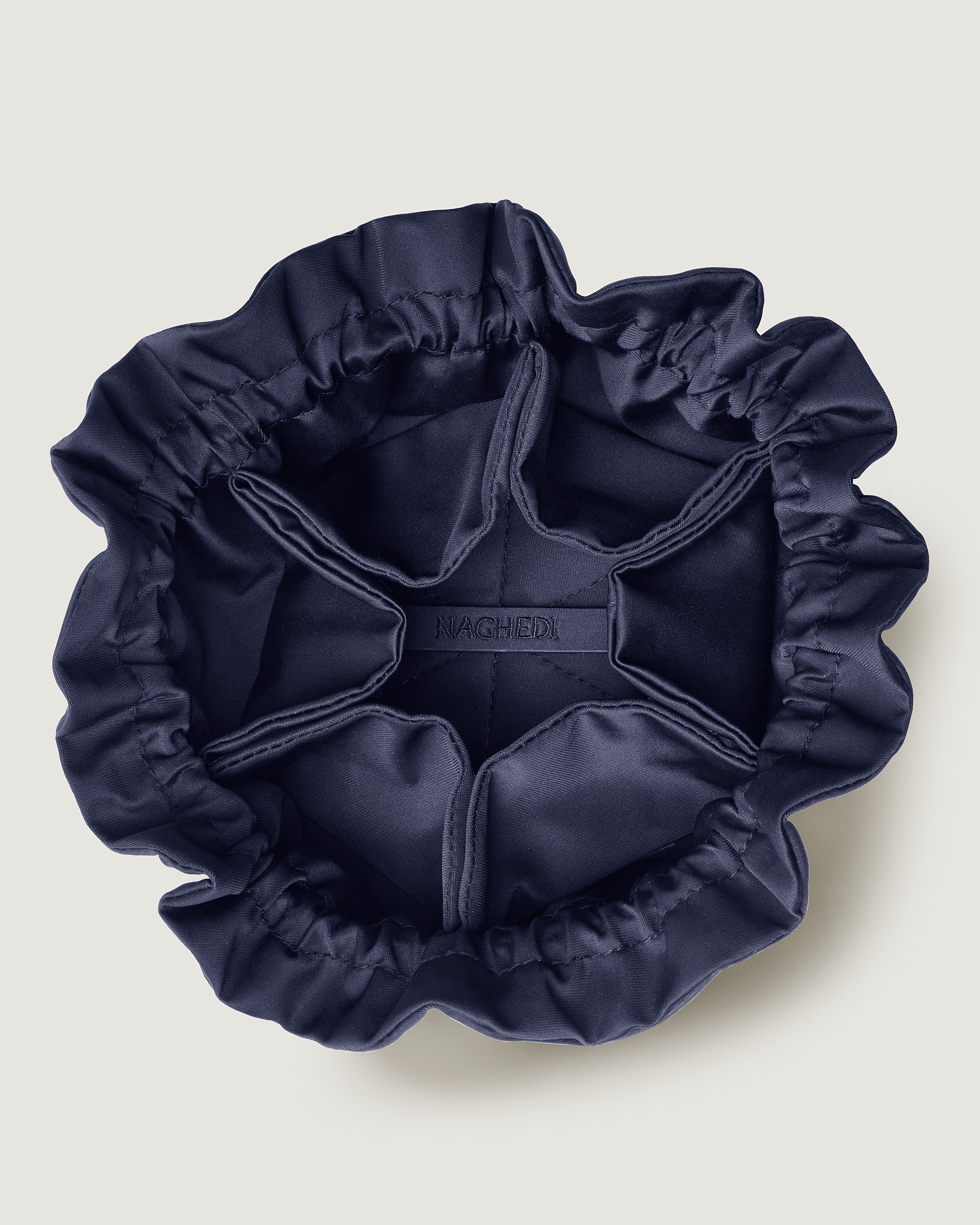 Interior close-up of Lotus Jewelry Pouch in Ink Blue showing its drawstring closure, one large center compartment and six small open interior pockets.