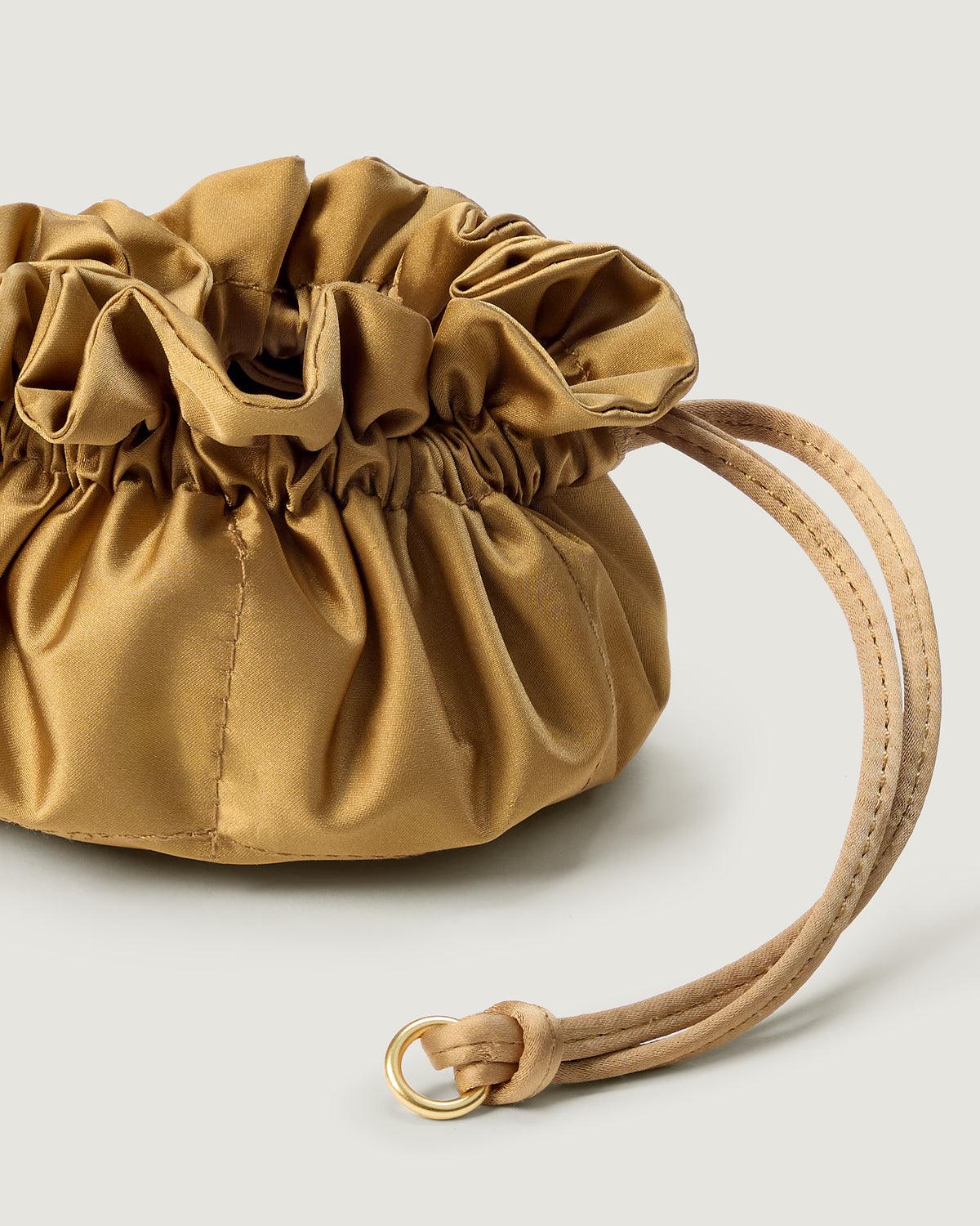 A close-up image of a small gold satin drawstring jewelry pouch.
