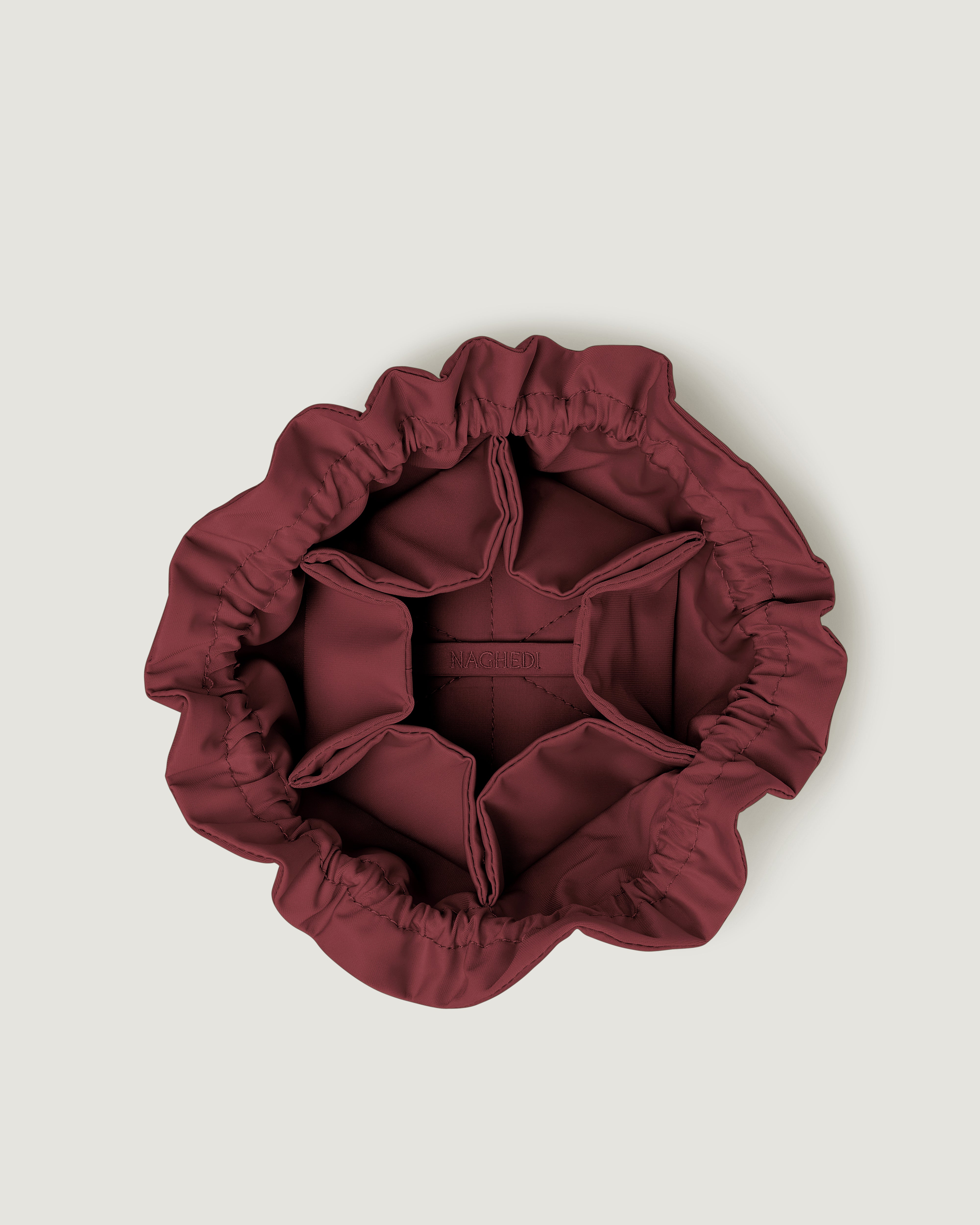 Inside view of a small burgundy neoprene drawstring jewelry pouch.