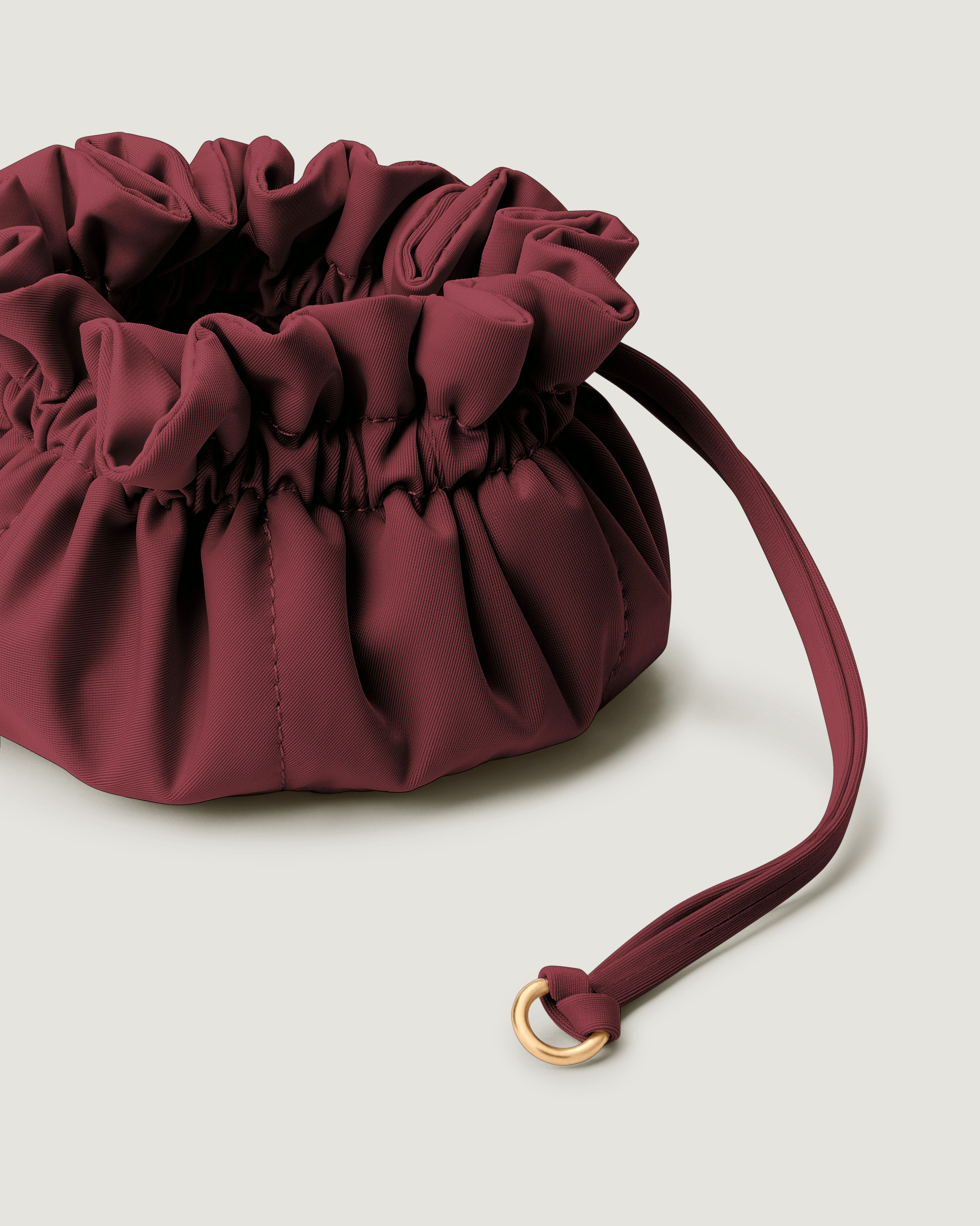 Close up image of a small burgundy neoprene drawstring jewelry pouch.