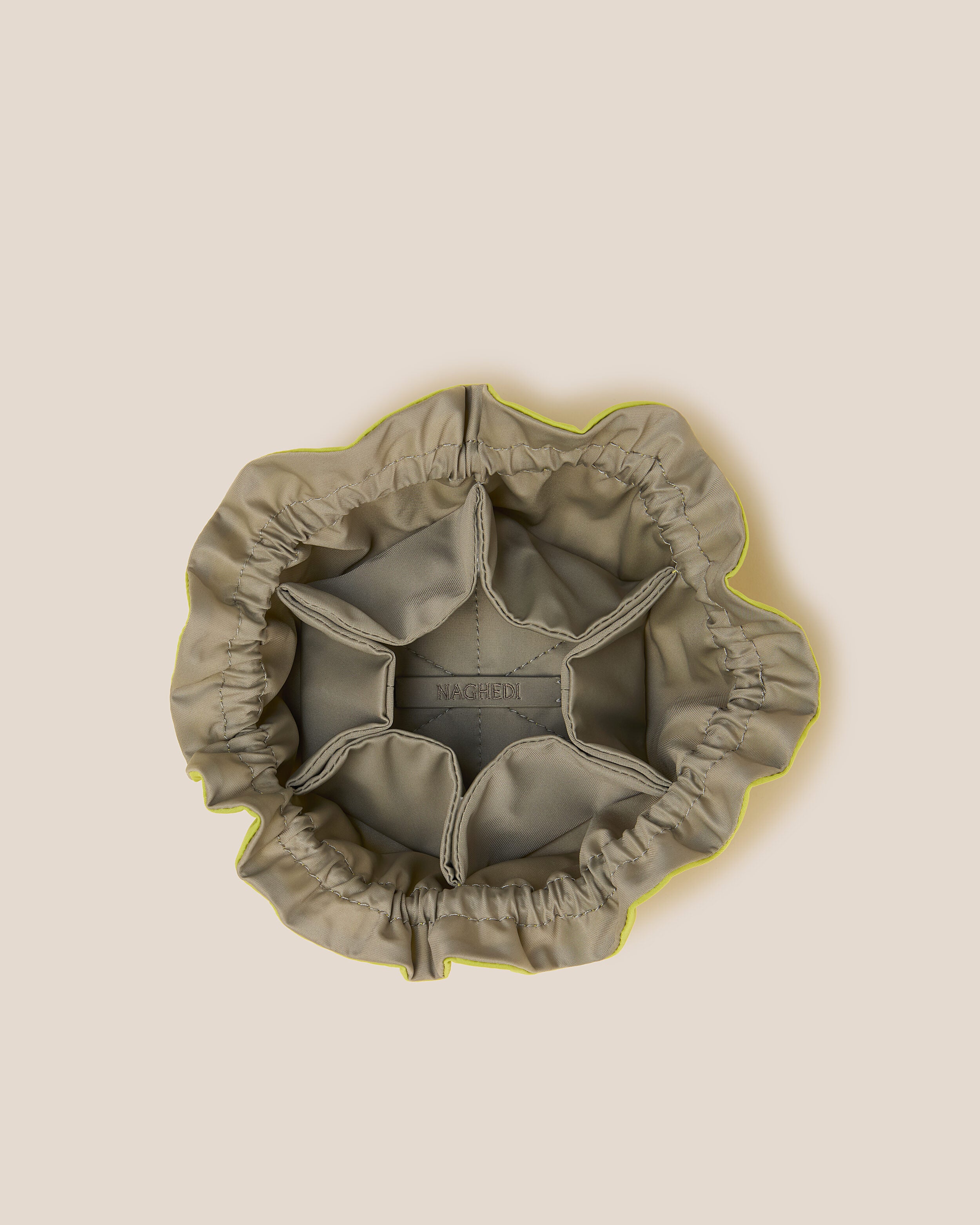 Interior close-up of Lotus Jewelry Pouch in Matcha (Lotus) showing its drawstring closure, one large center compartment. six small open interior pockets, and contrast neoprene interior.