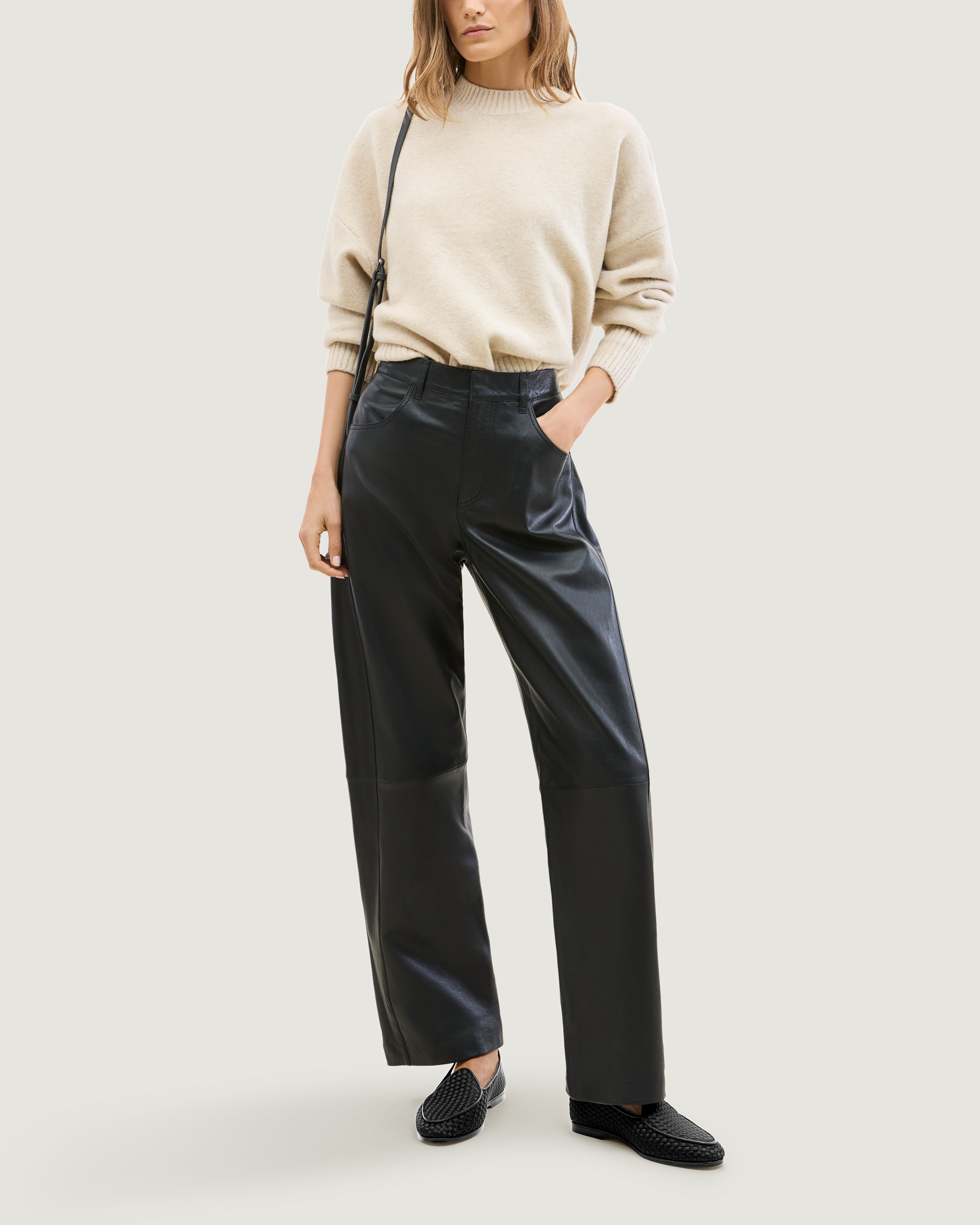 Full body shot of model wearing handwoven satin slip-on loafers against a light gray background.