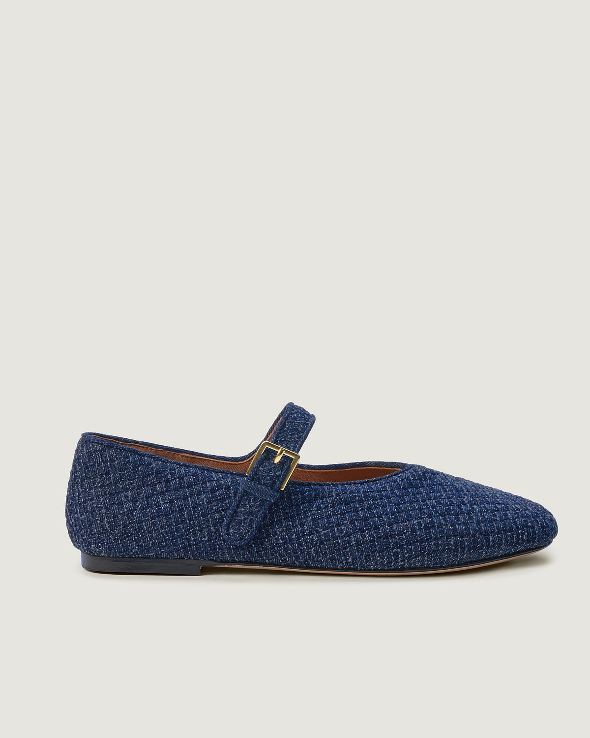 Side view of The Marais Mary Jane in Denim, an indigo tone, featuring a closed toe and round silhouette, and an adjustable strap with buckle closure.