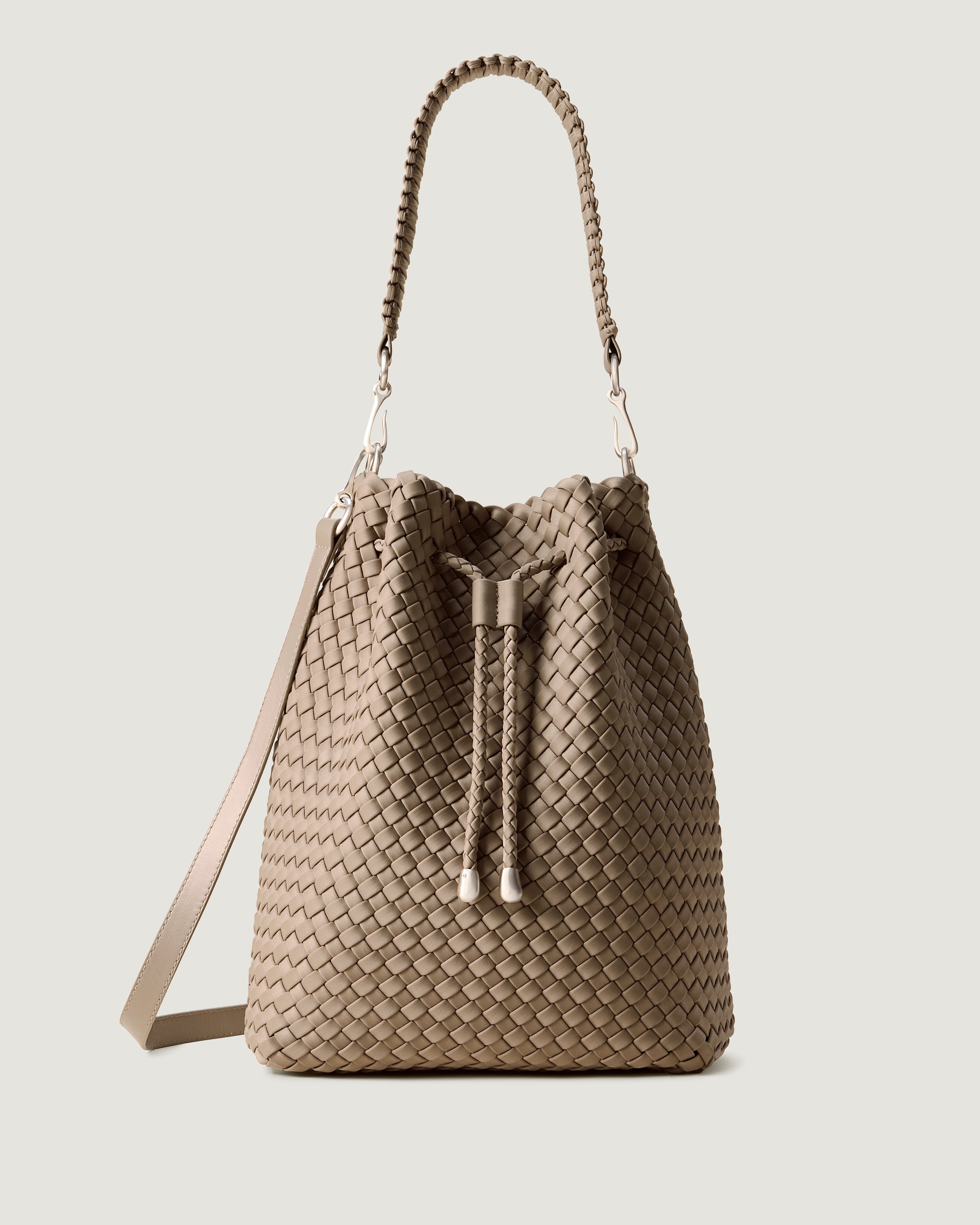 Mercer Bucket in Cashmere, a taupe tone, in handwoven neoprene, featuring a drawstring closure, and removable, adjustable leather crossbody strap.