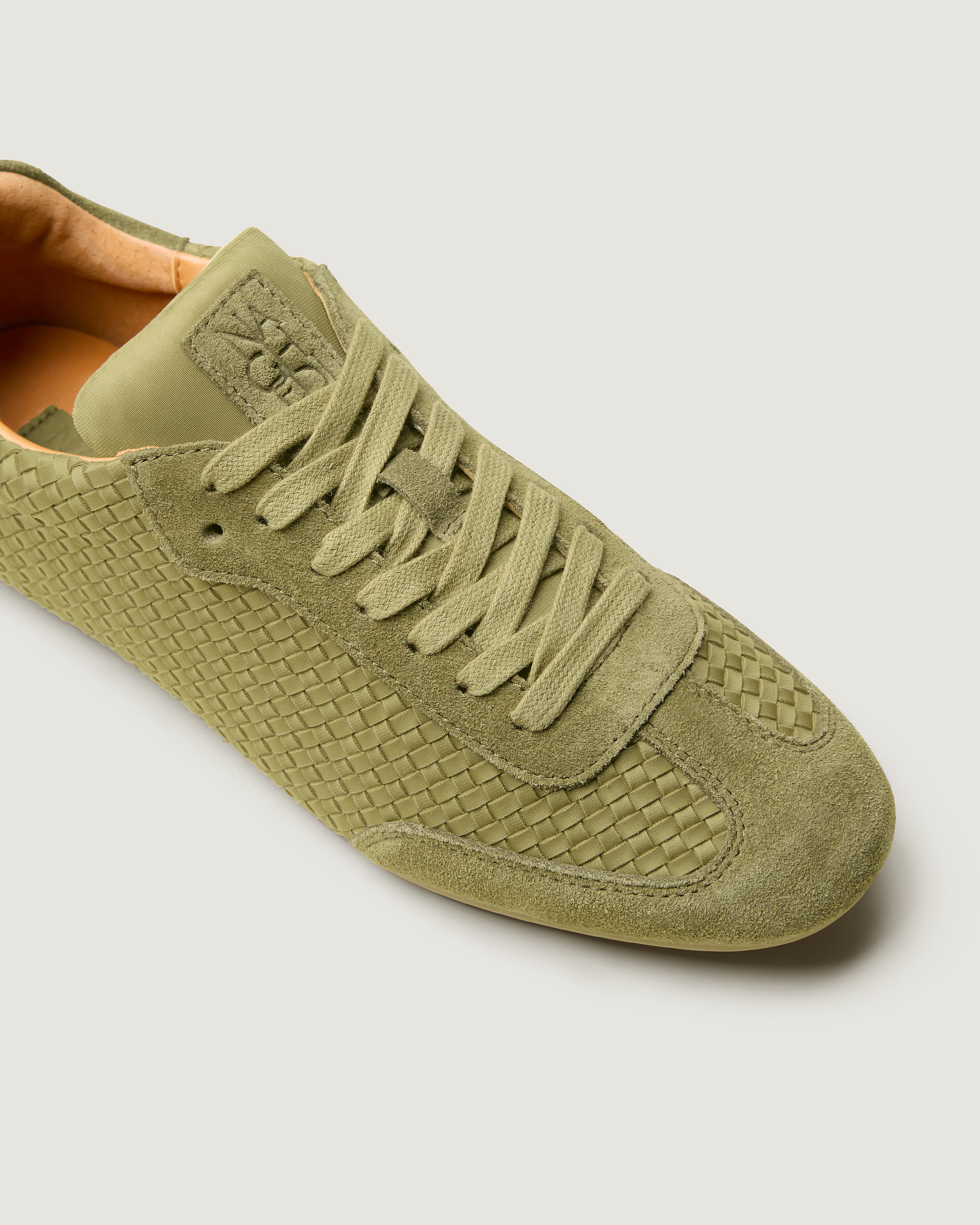 Close-up of The Milan Sneaker in Bottle Green showing its tonal suede trim.