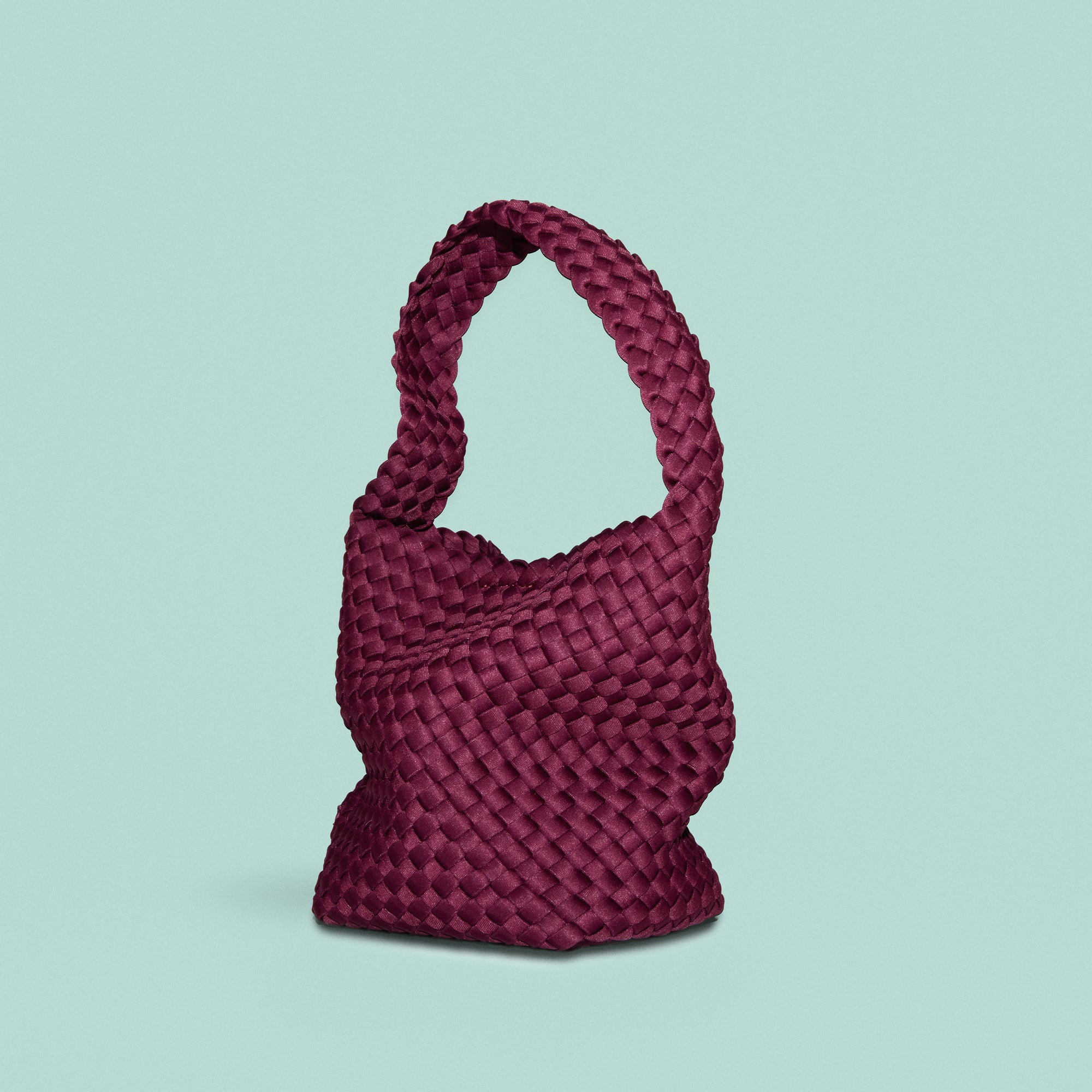 Nomad Hobo in Bordeaux, a rich burgundy tone, in handwoven neoprene, featuring an open top with magnetic snap closure, and handwoven shoulder strap lays comfortably flat.