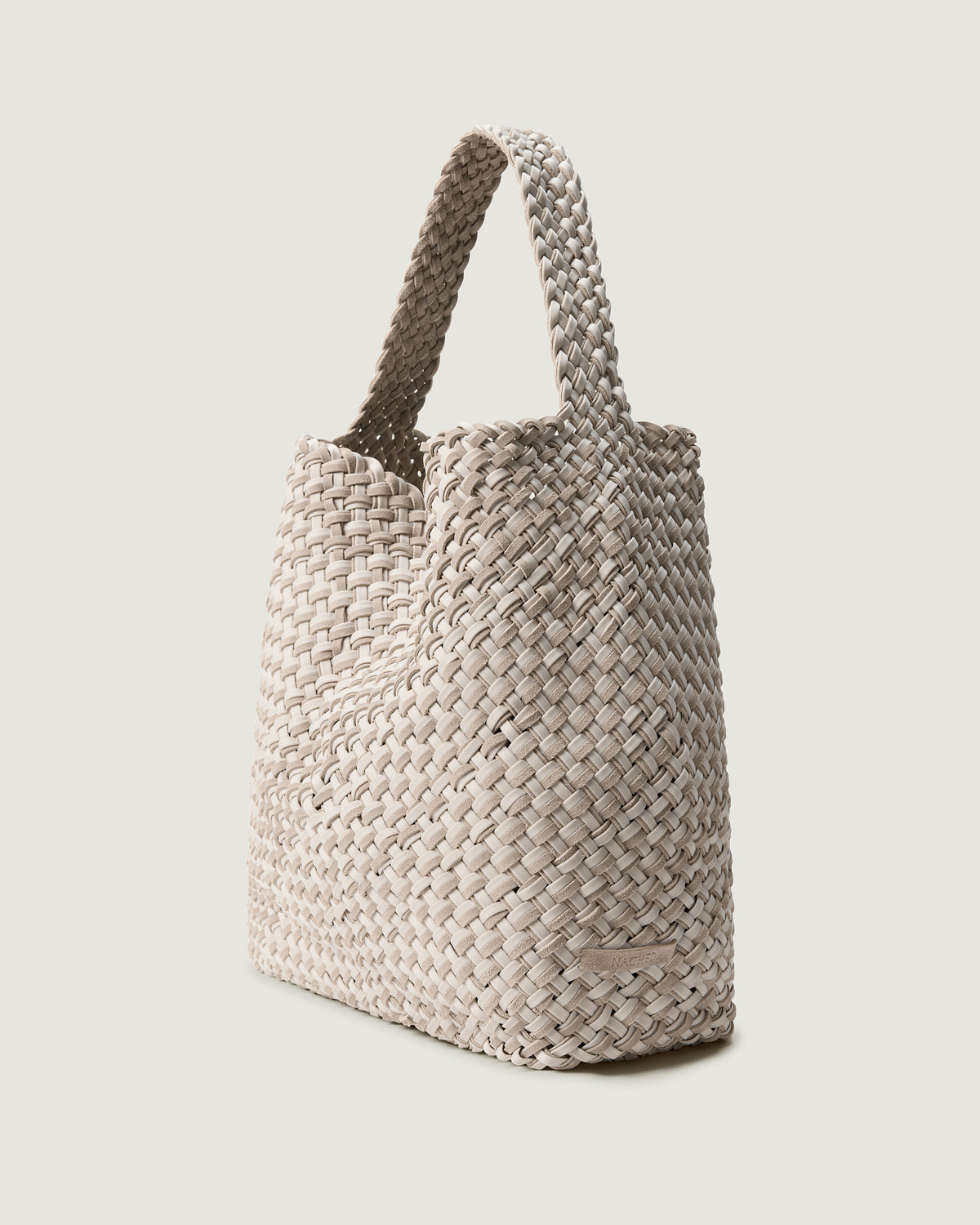 Nomad Large Hobo in Linen shown from a side angle, highlighting its handwoven neoprene and suede construction and open top with magnetic snap closure.