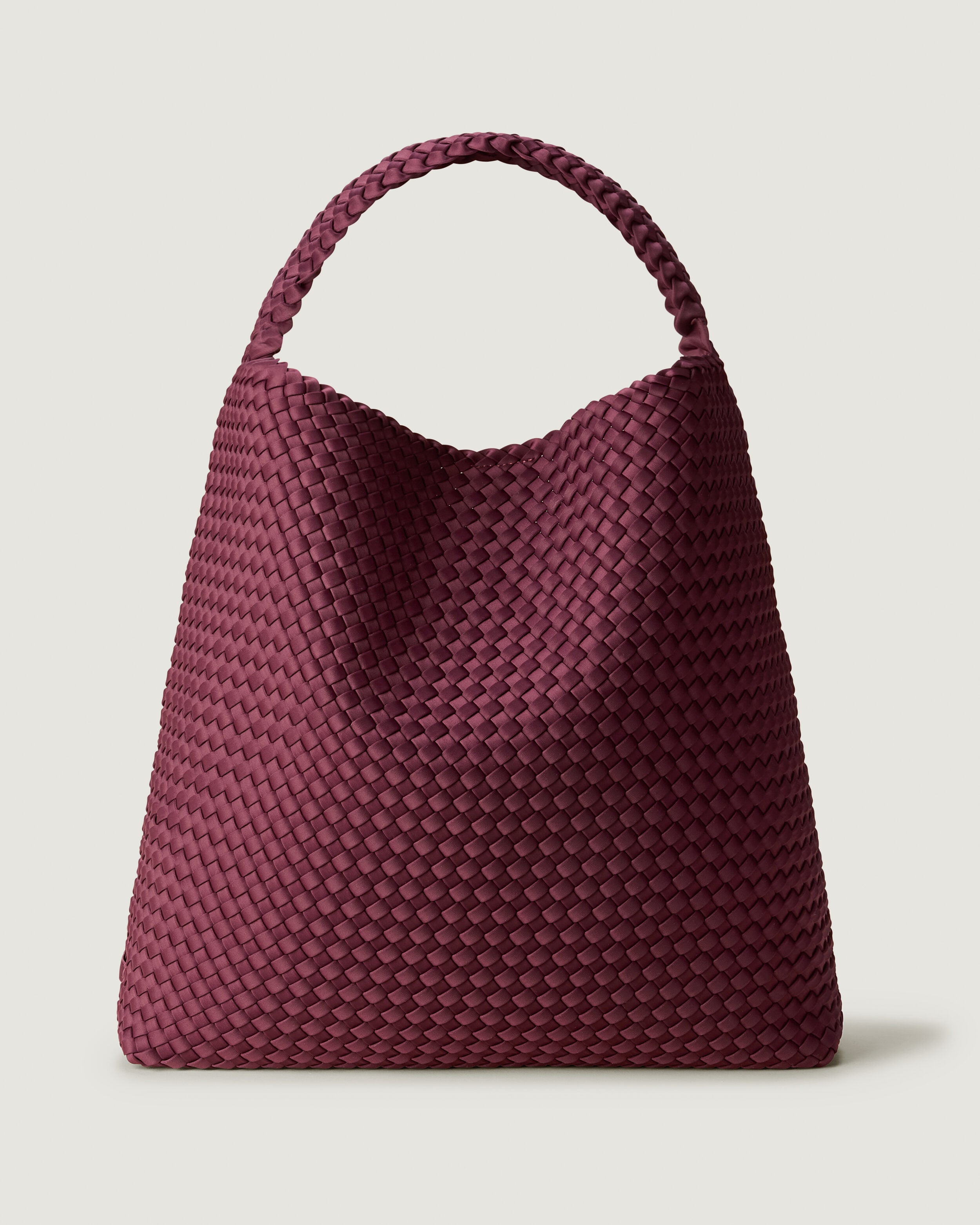 Nomad Hobo in Bordeaux, a rich burgundy tone, in handwoven neoprene, featuring an open top with magnetic snap closure, and handwoven shoulder strap lays comfortably flat.