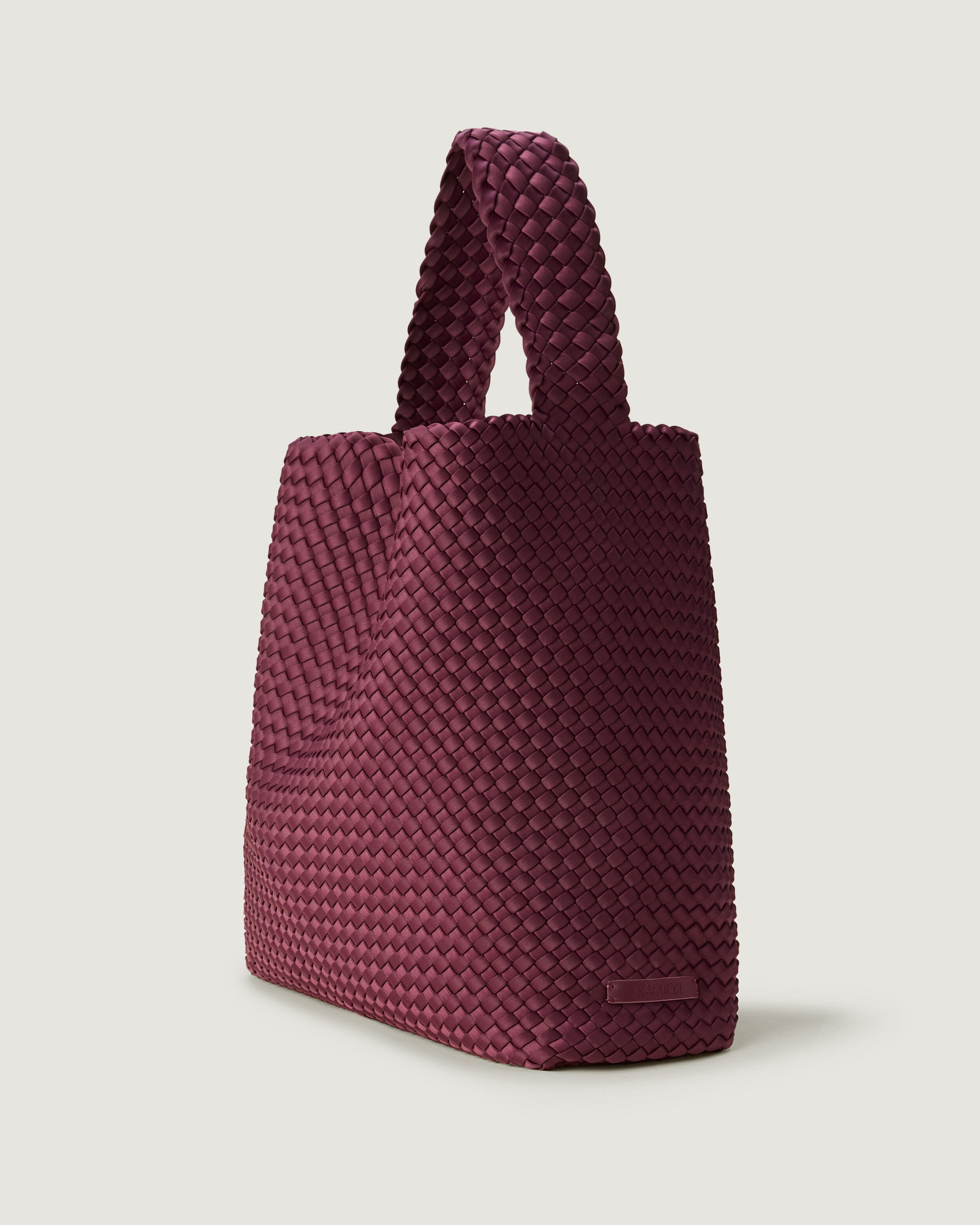 Nomad Hobo in Bordeaux shown from a side angle, highlighting its handwoven neoprene construction and open top with magnetic snap closure.