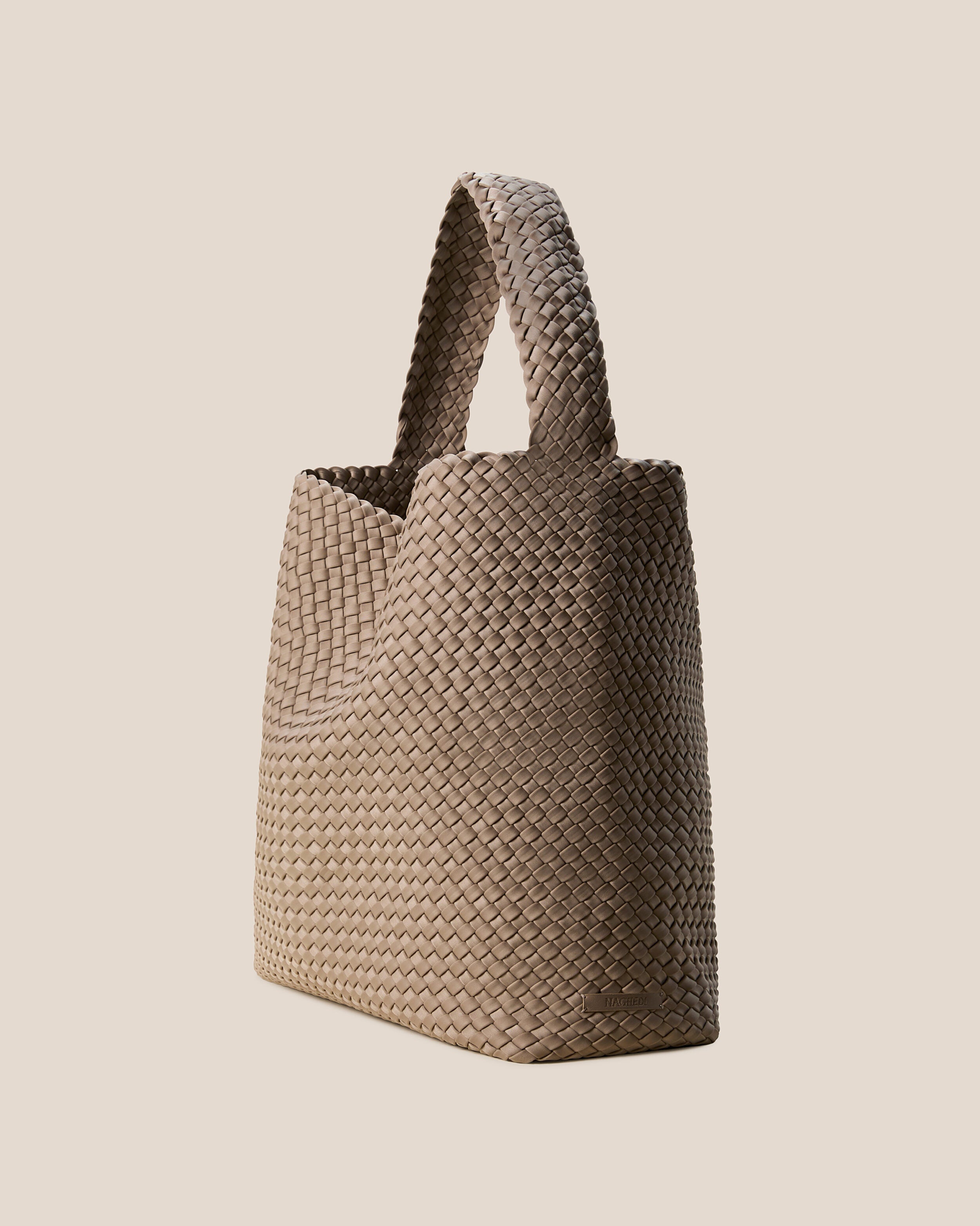 Nomad Hobo in Cashmere shown from a side angle, highlighting its handwoven neoprene construction and open top with magnetic snap closure.