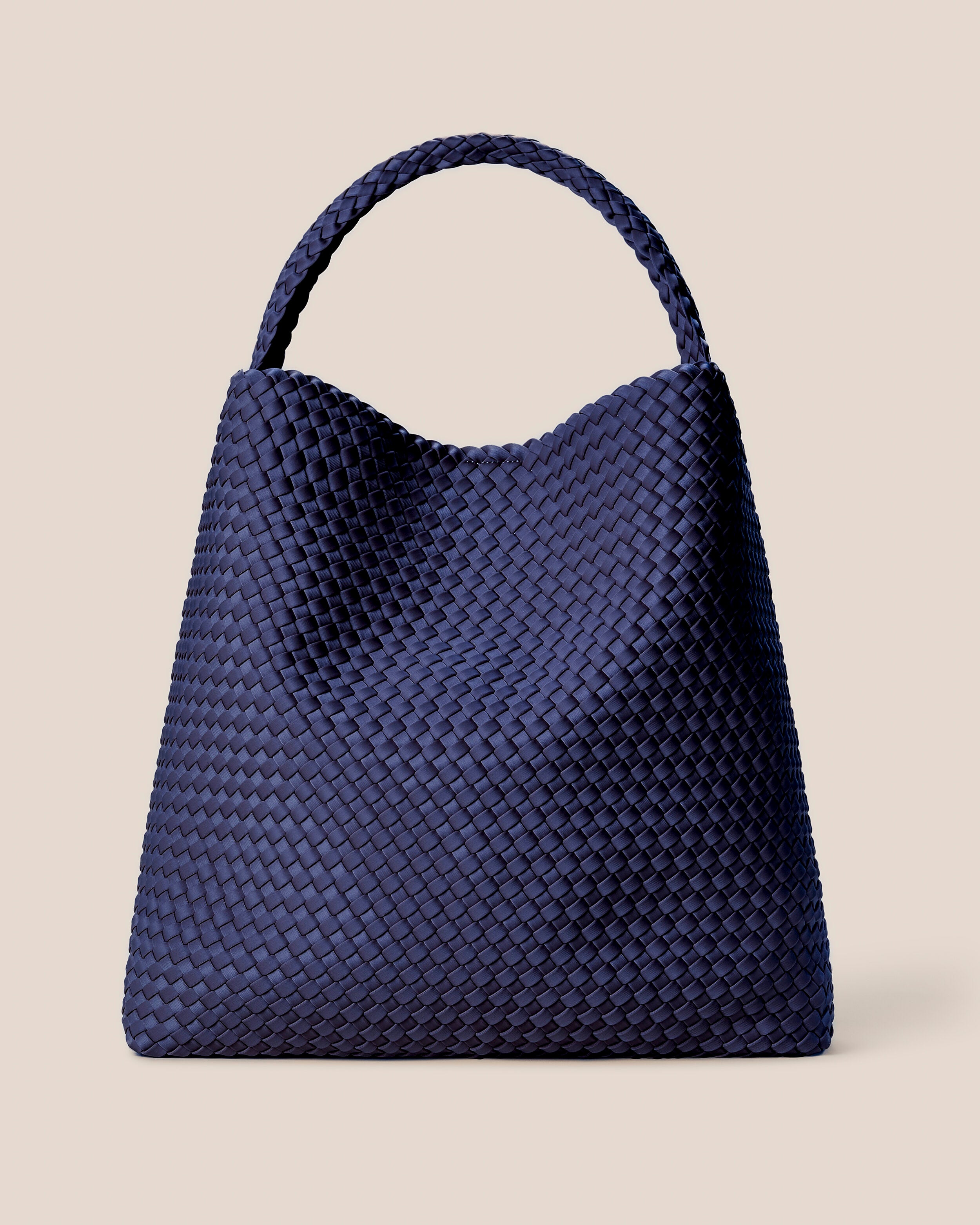 Nomad Hobo in Ink Blue, a navy blue tone, in handwoven neoprene, featuring an open top with magnetic snap closure, and handwoven shoulder strap lays comfortably flat.