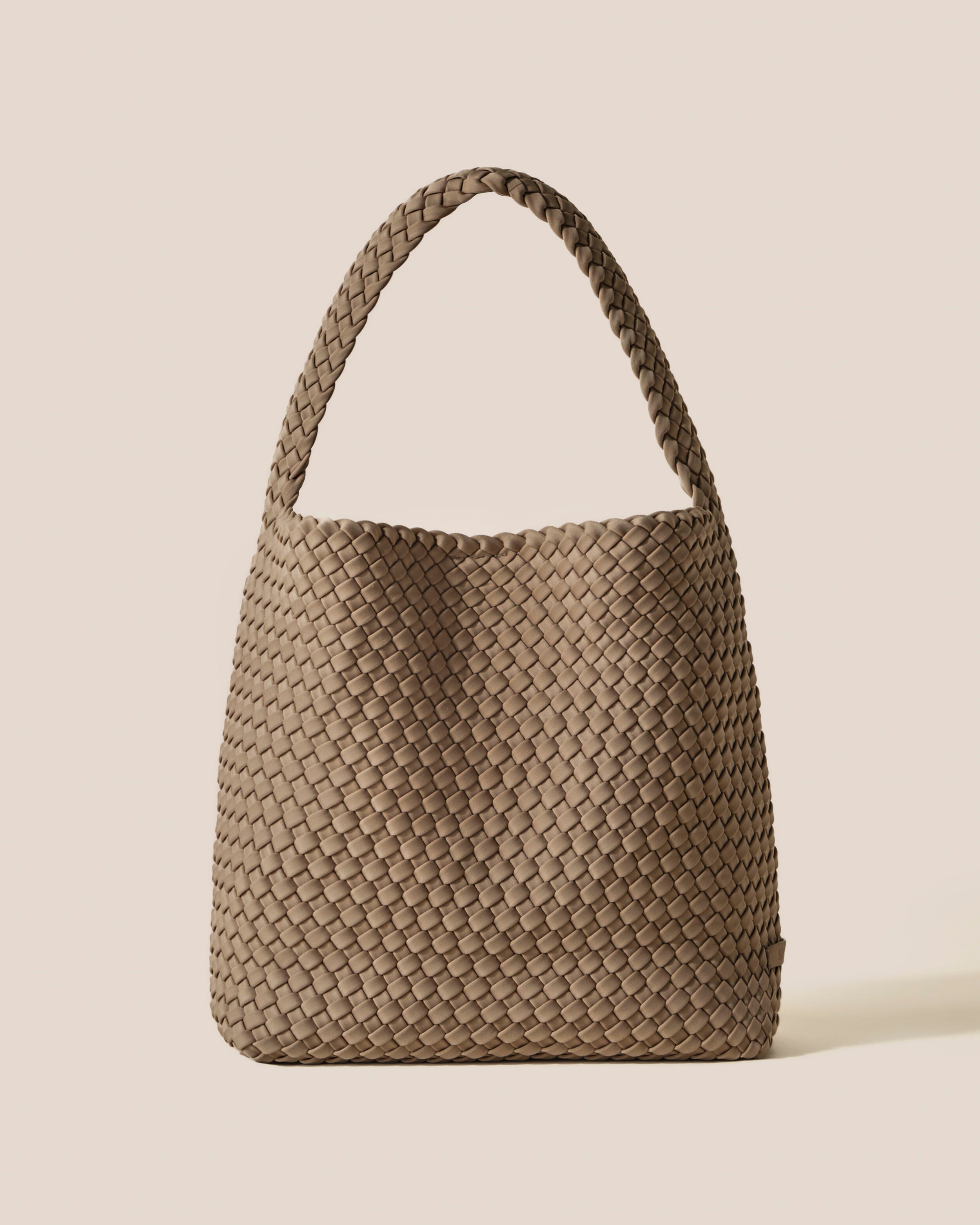 Nomad Hobo in Cashmere, a taupe tone, in handwoven neoprene, featuring an open top with magnetic snap closure, and handwoven shoulder strap lays comfortably flat.