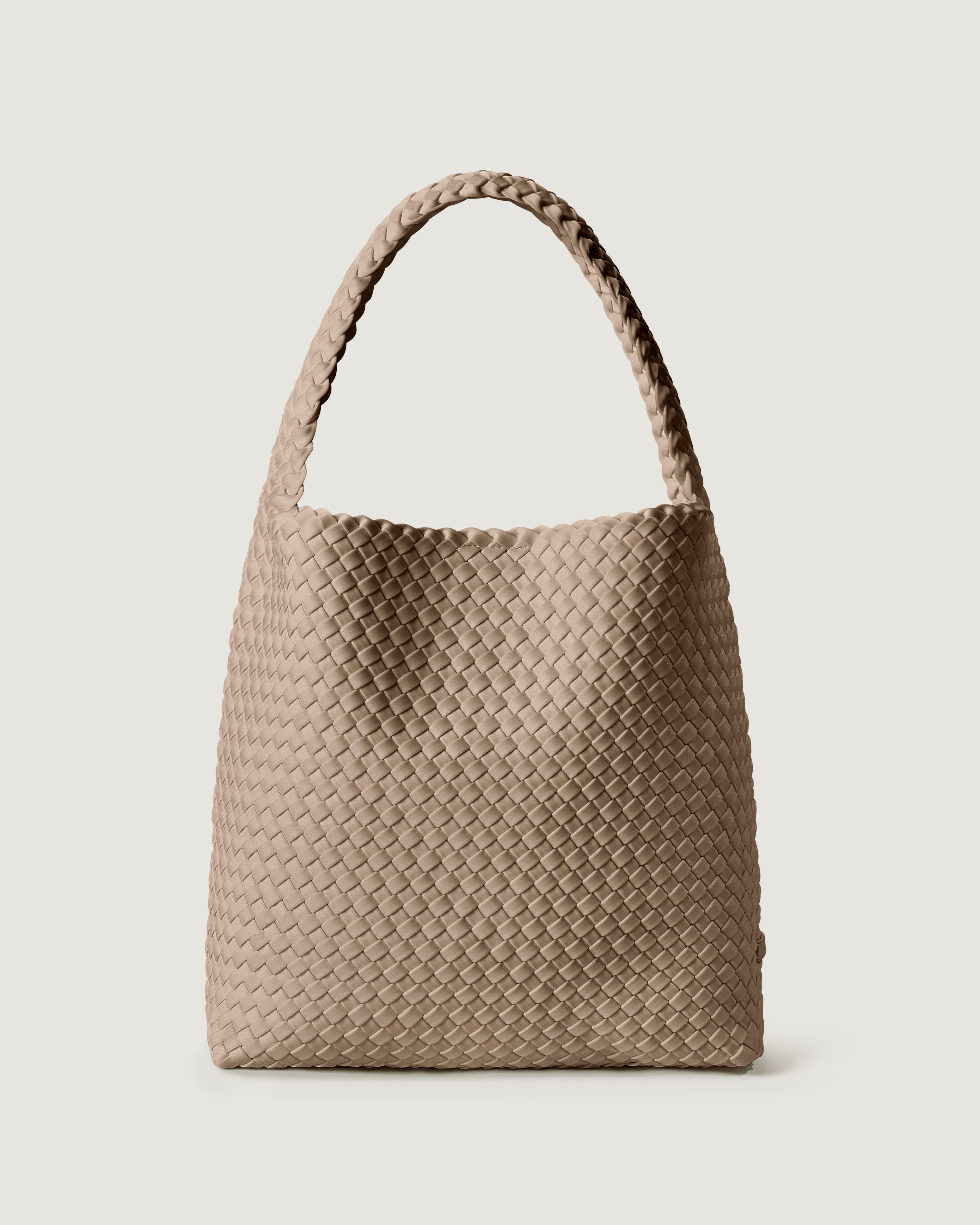 Nomad Hobo in Cashmere, a taupe tone, in handwoven neoprene, featuring an open top with magnetic snap closure, and handwoven shoulder strap lays comfortably flat.