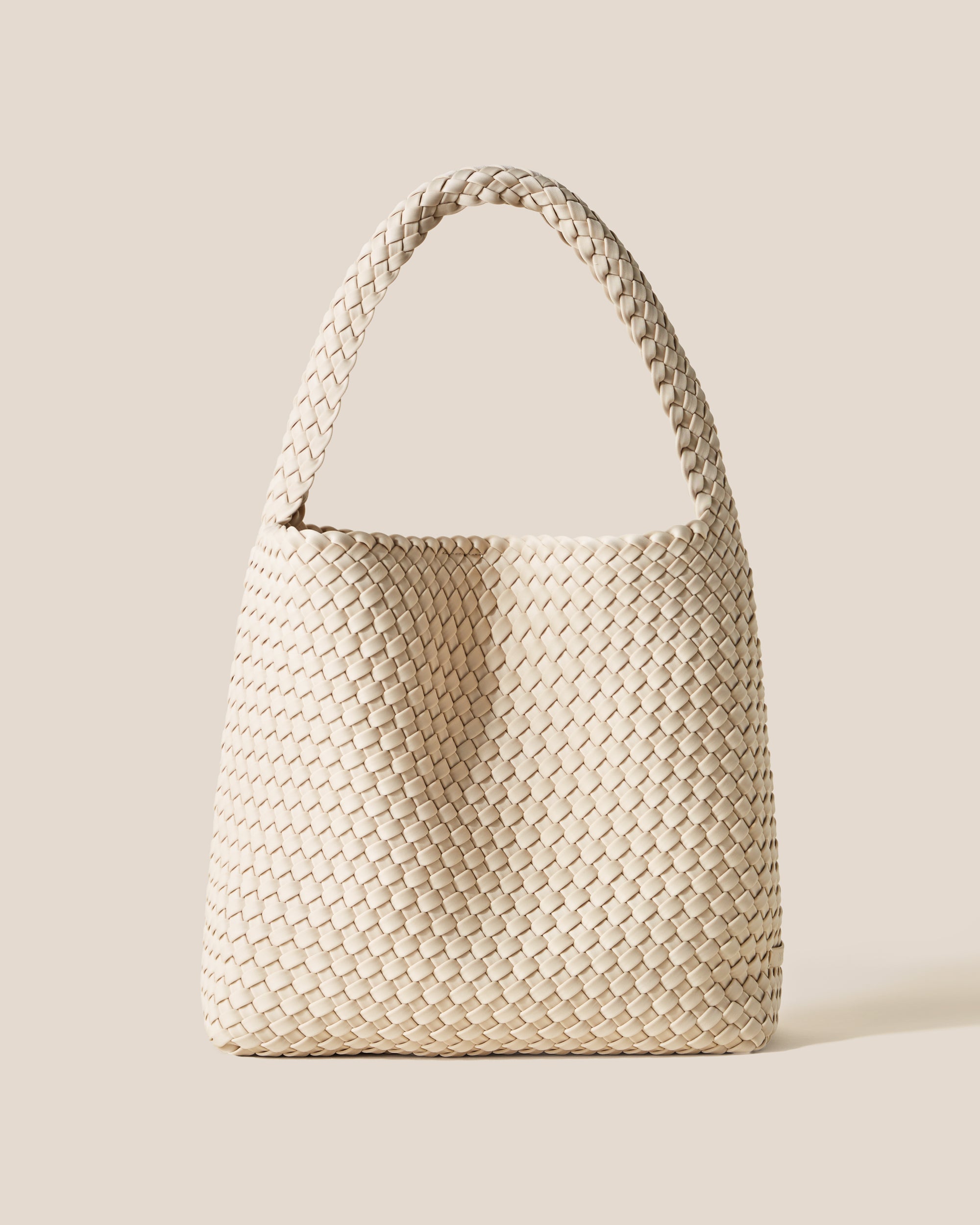 Nomad Medium Hobo Bag in Ecru, a cream tone, in handwoven neoprene featuring an open top with magnetic snap closure, and handwoven shoulder strap lays comfortably flat.
