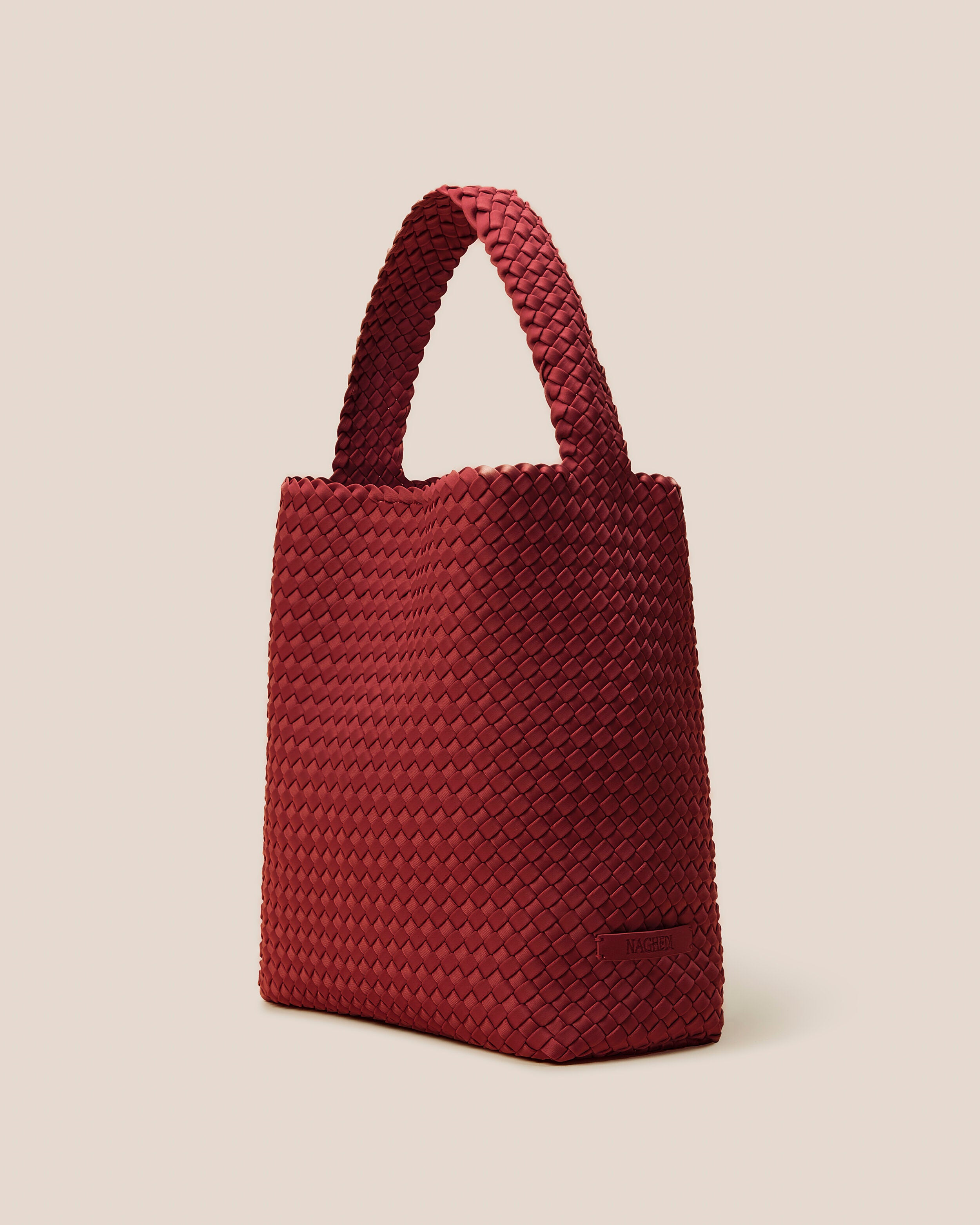 Nomad Hobo in Rosso shown from a side angle, highlighting its handwoven neoprene construction and open top with magnetic snap closure.