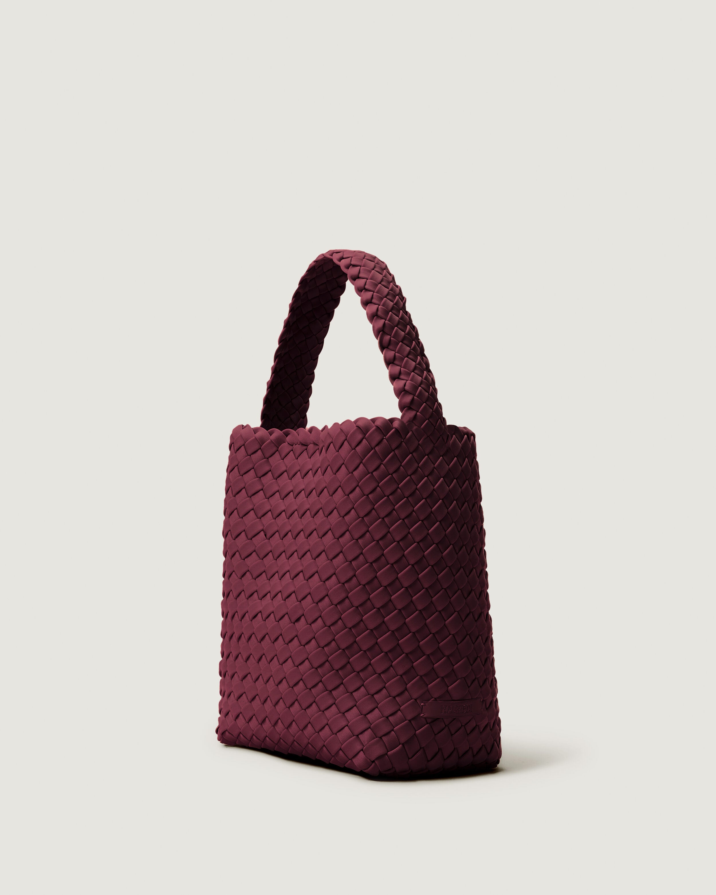 Nomad Hobo in Bordeaux shown from a side angle, highlighting its handwoven neoprene construction and open top with magnetic snap closure.