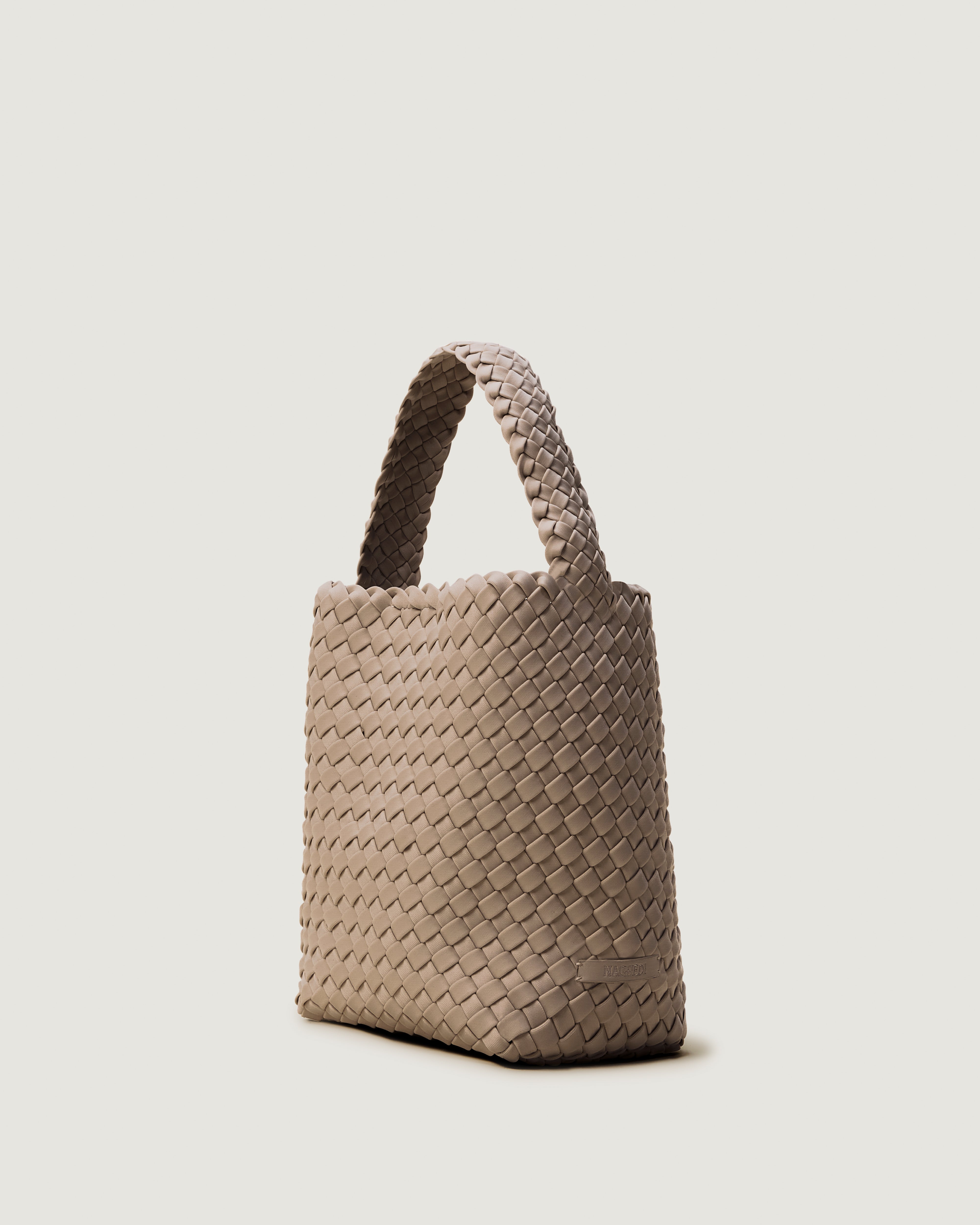 Nomad Hobo in Cashmere shown from a side angle, highlighting its handwoven neoprene construction and open top with magnetic snap closure.