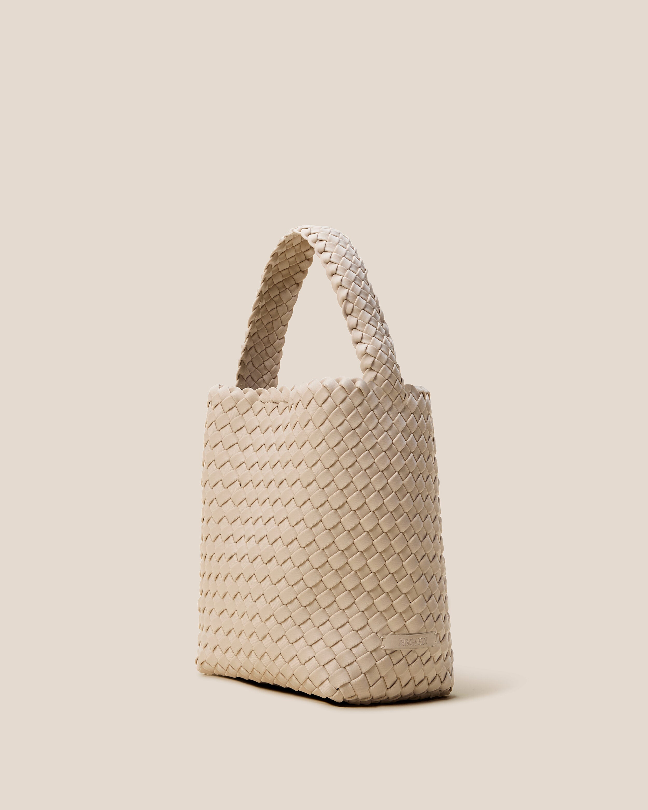 Nomad Hobo in Ecru shown from a side angle, highlighting its handwoven neoprene construction and open top with magnetic snap closure.