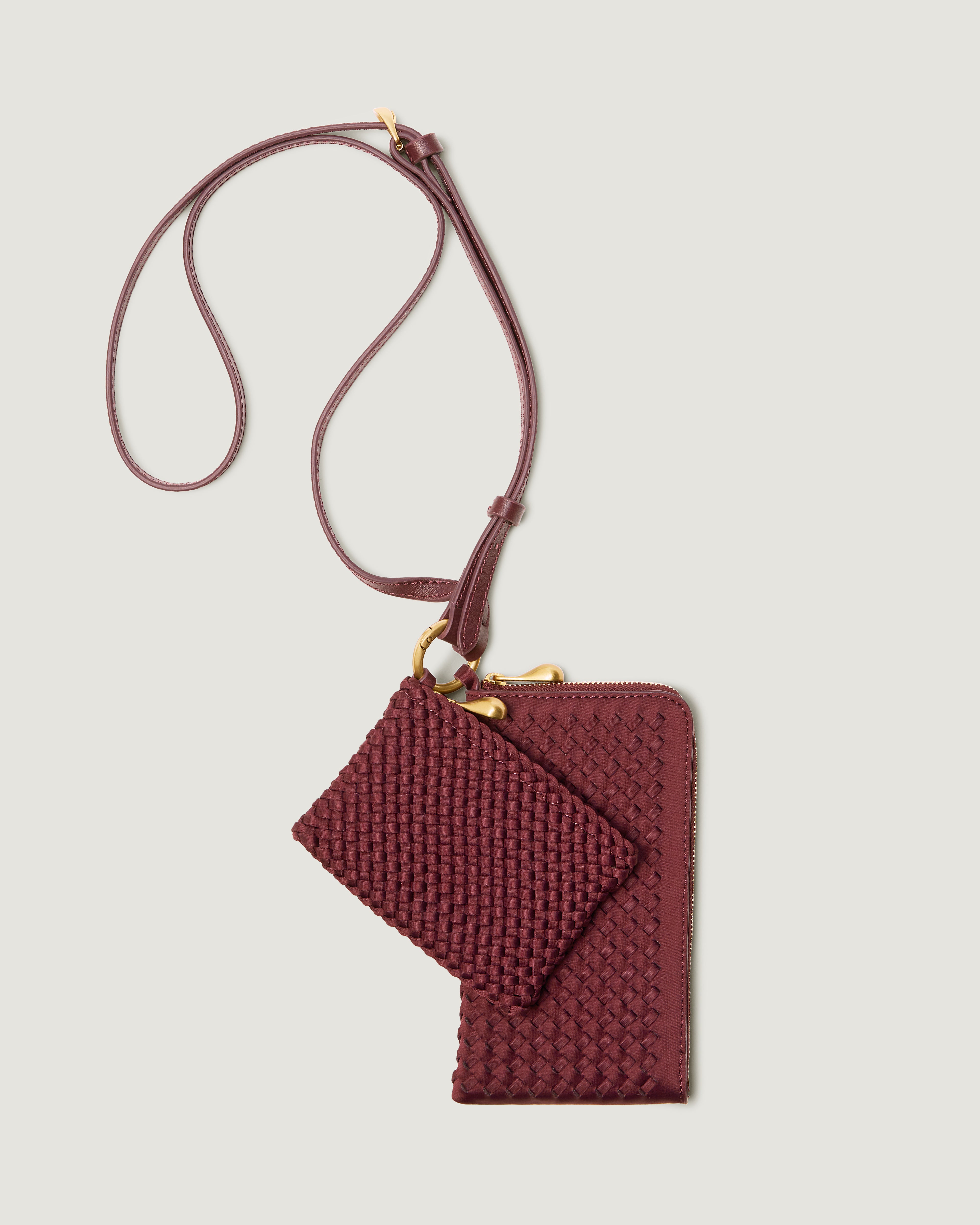 A handwoven neoprene crossbody zippered phone case in a burgundy color, featuring a matching zippered card holder pouch and a thin adjustable shoulder strap.