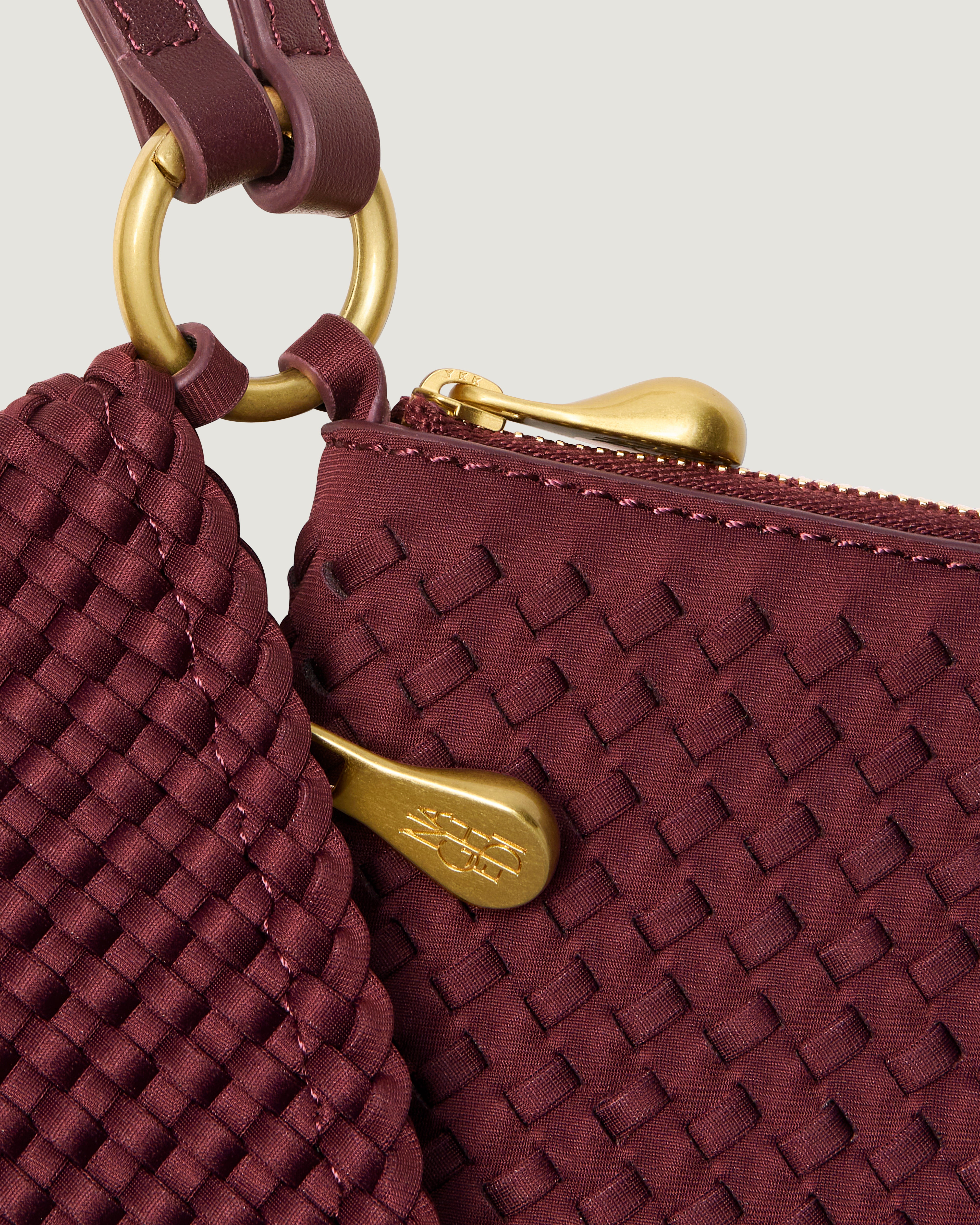 Close up image of hardware on Orly Phone Case, brushed gold zipper pulls and connector rings.