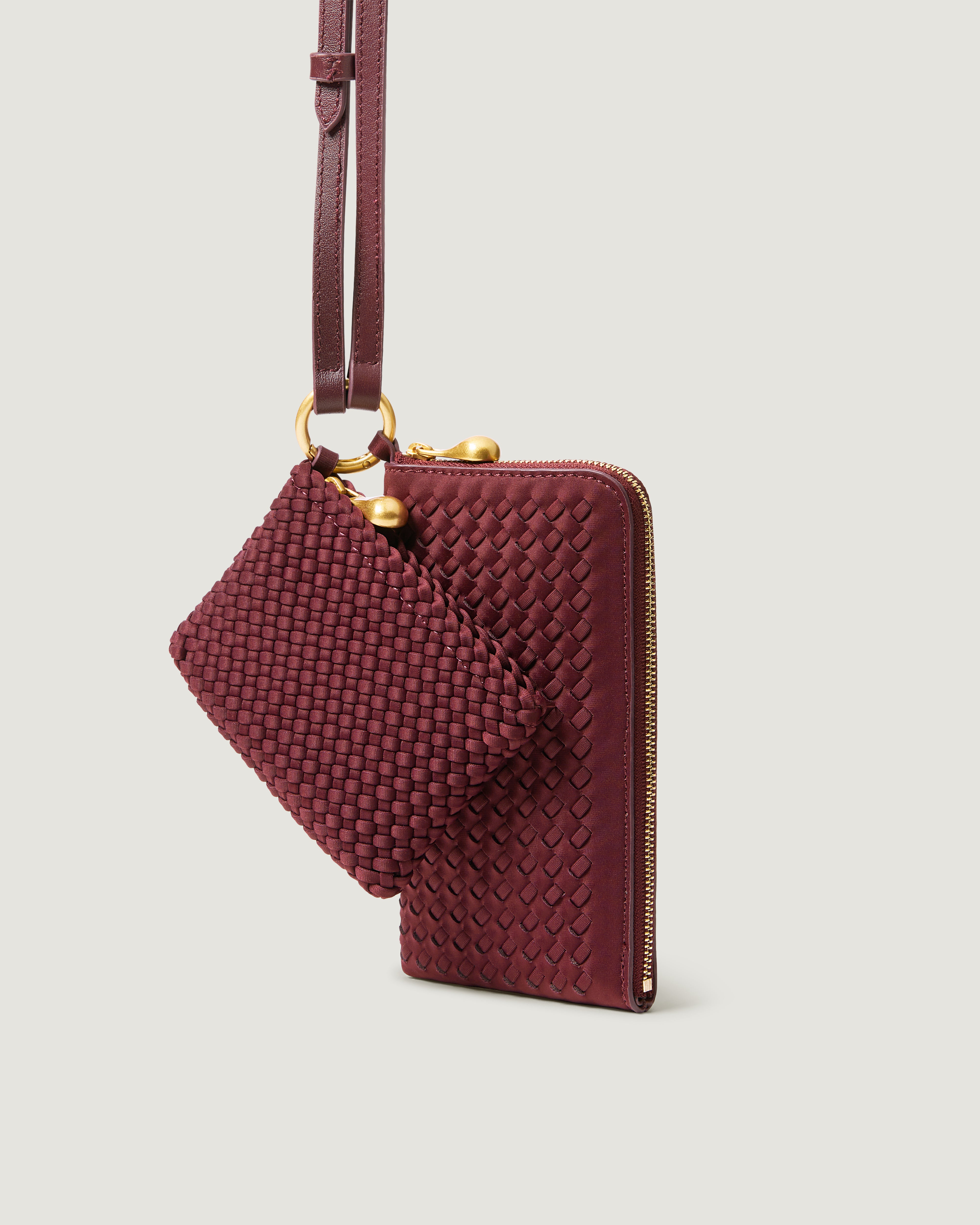 A handwoven neoprene crossbody zippered phone case in a burgundy color, featuring a matching zippered card holder pouch and a thin adjustable shoulder strap.