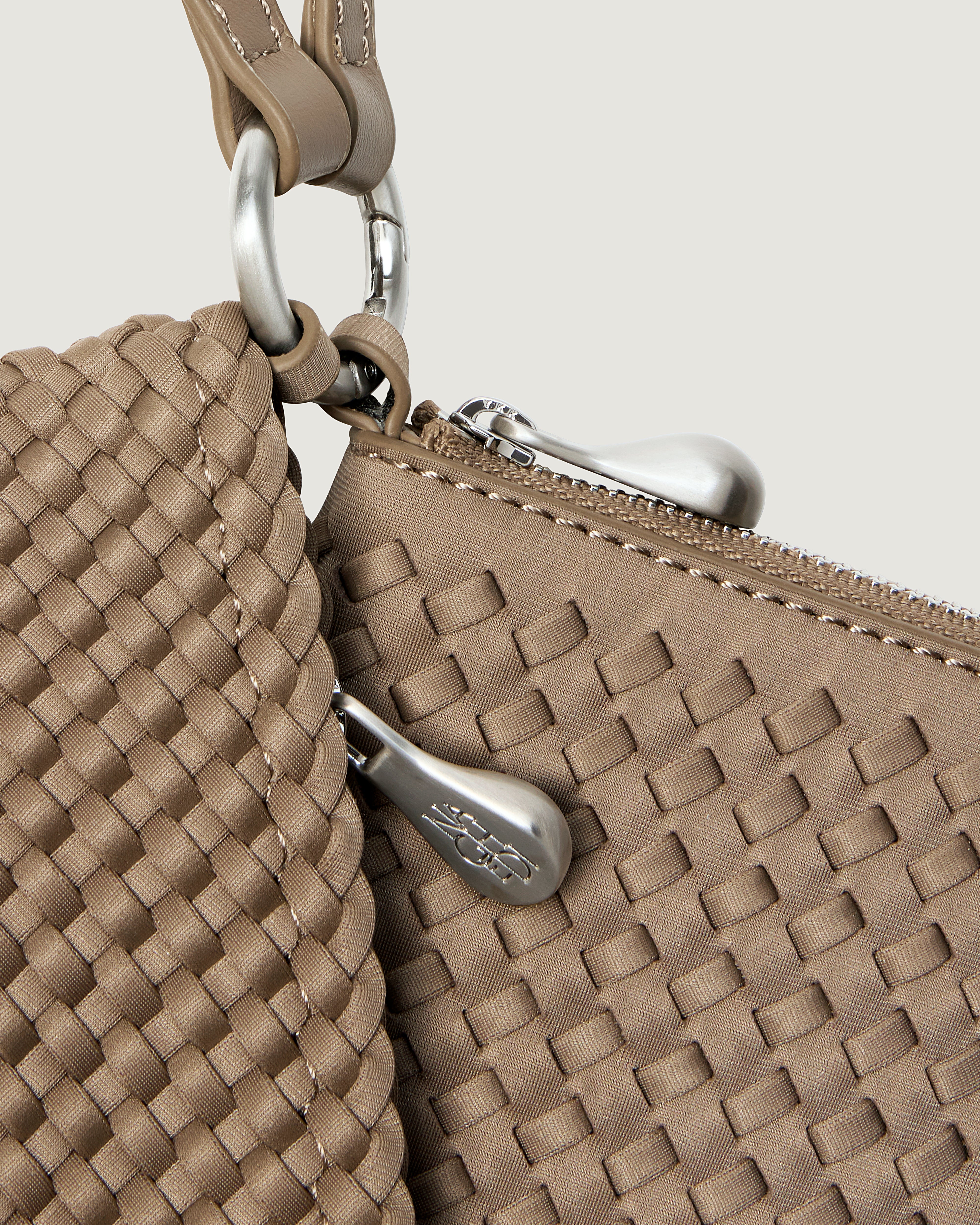 Close up image of hardware on Orly Phone Case, brushed silver zipper pulls and connector rings.