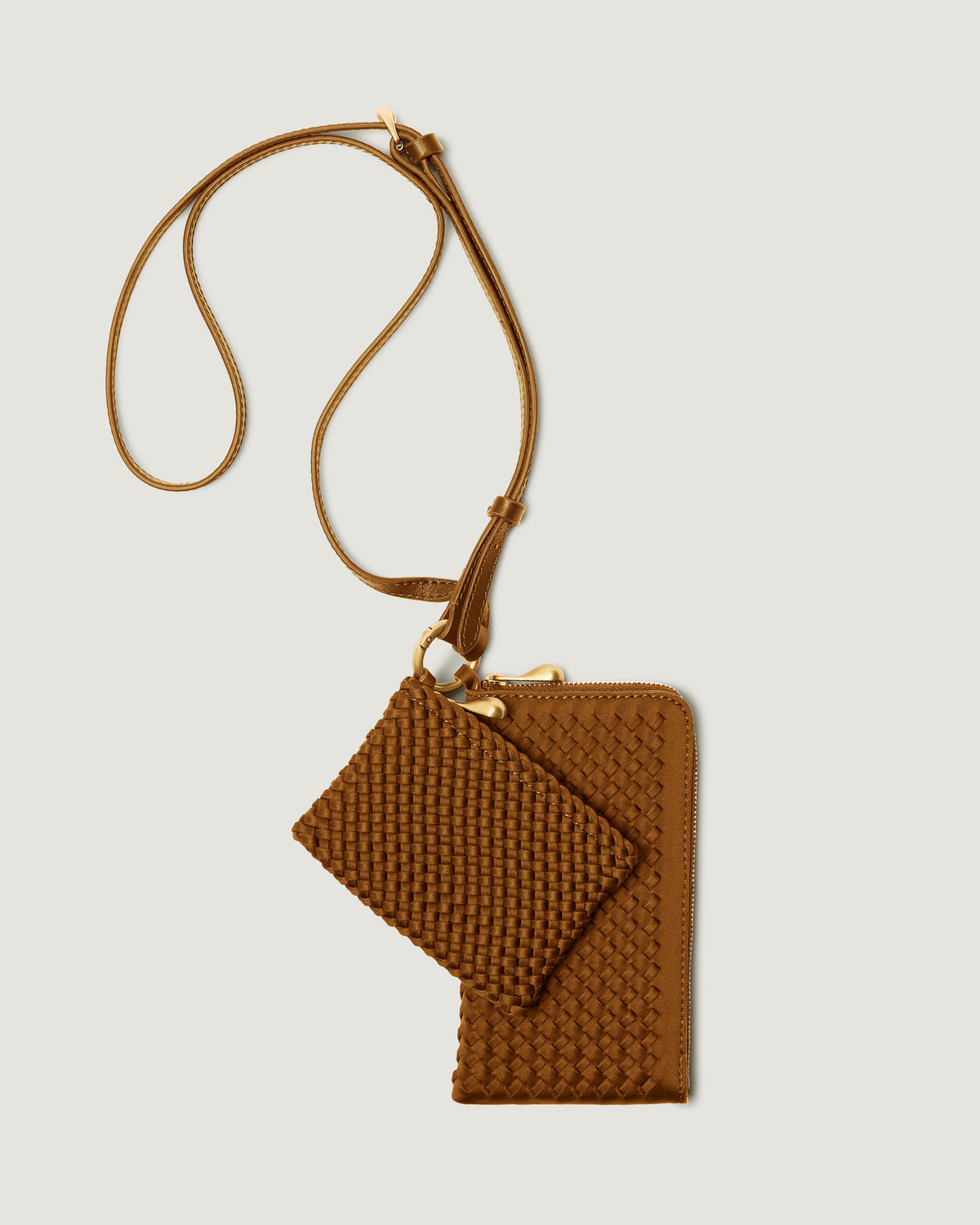 A handwoven neoprene crossbody zippered phone case in a saddle brown color, featuring a matching zippered card holder pouch and a thin adjustable shoulder strap.