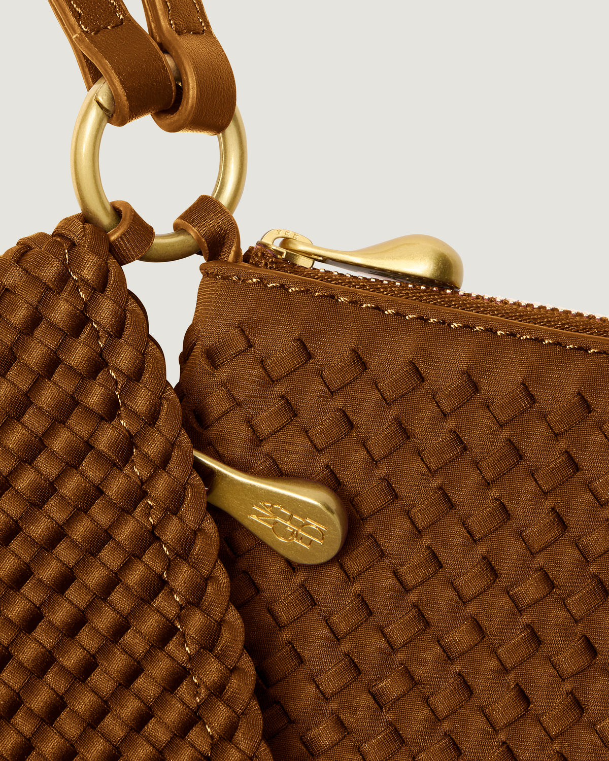 Close up image of hardware on Orly Phone Case, brushed gold zipper pulls and connector rings.