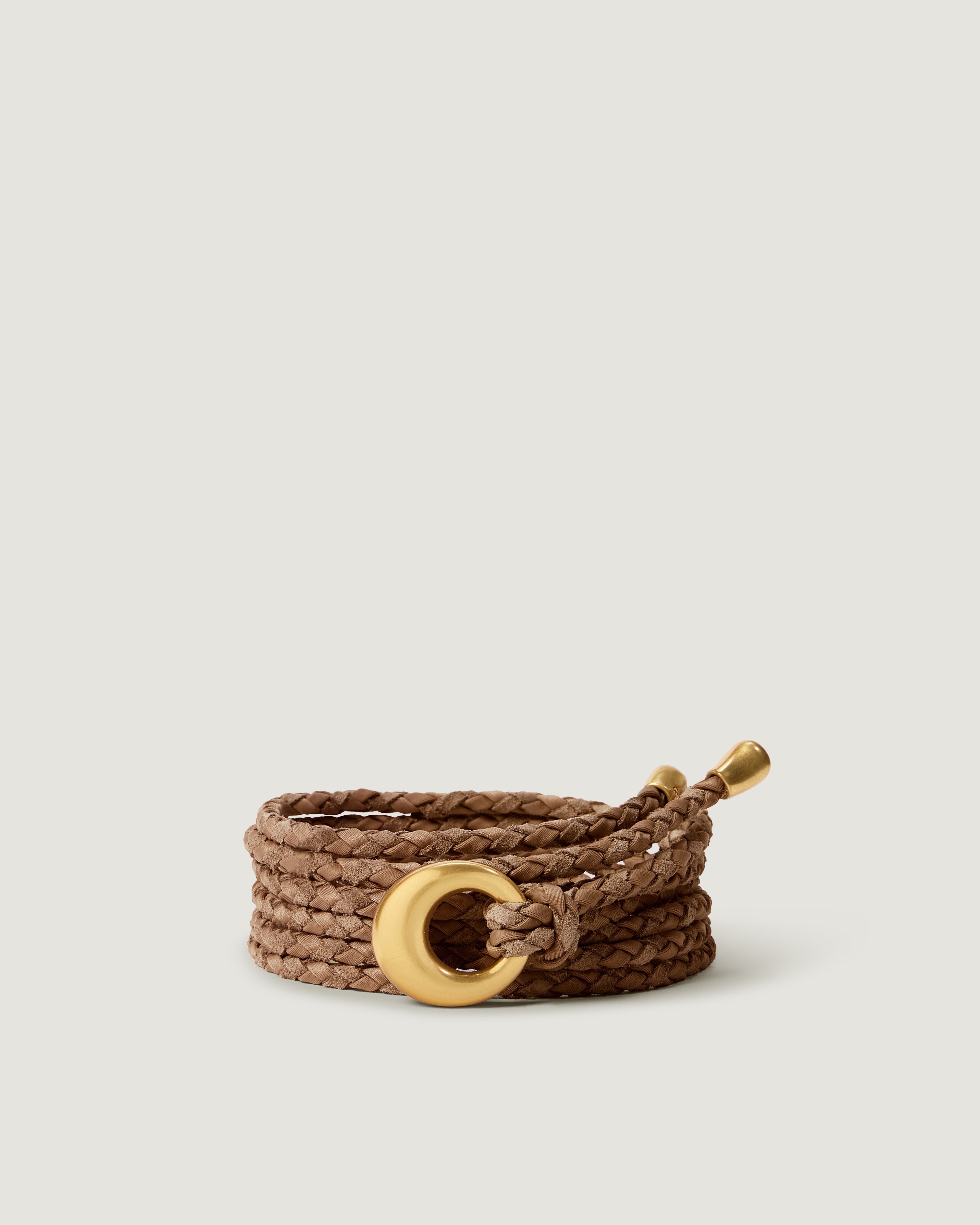 A light brown handwoven neoprene and suede braided rope belt with a gold metal ring closure and matching gold-toned tips.