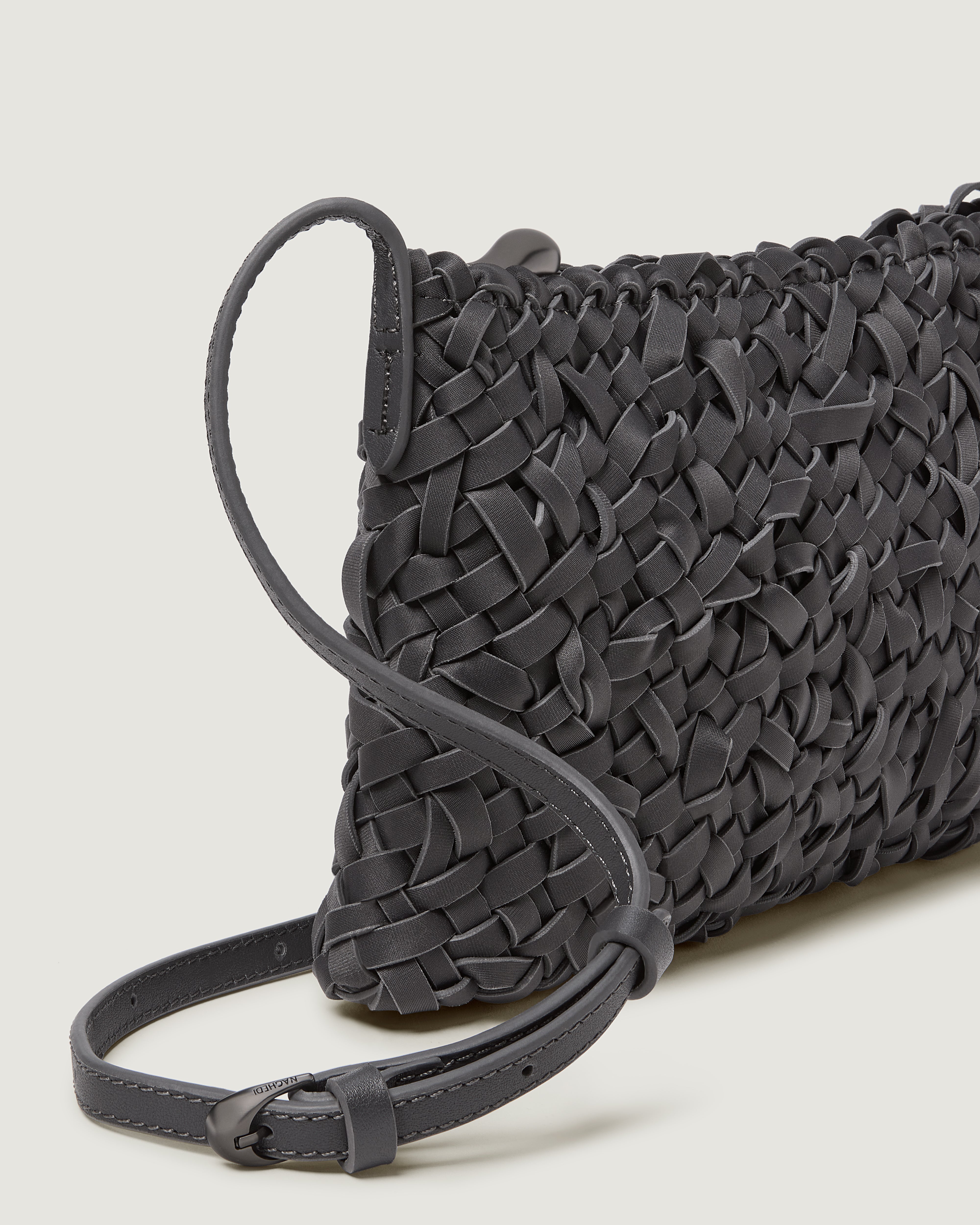 A close-up of a handwoven neoprene crossbody bag in ash gray color with a crosshatch nest weave pattern