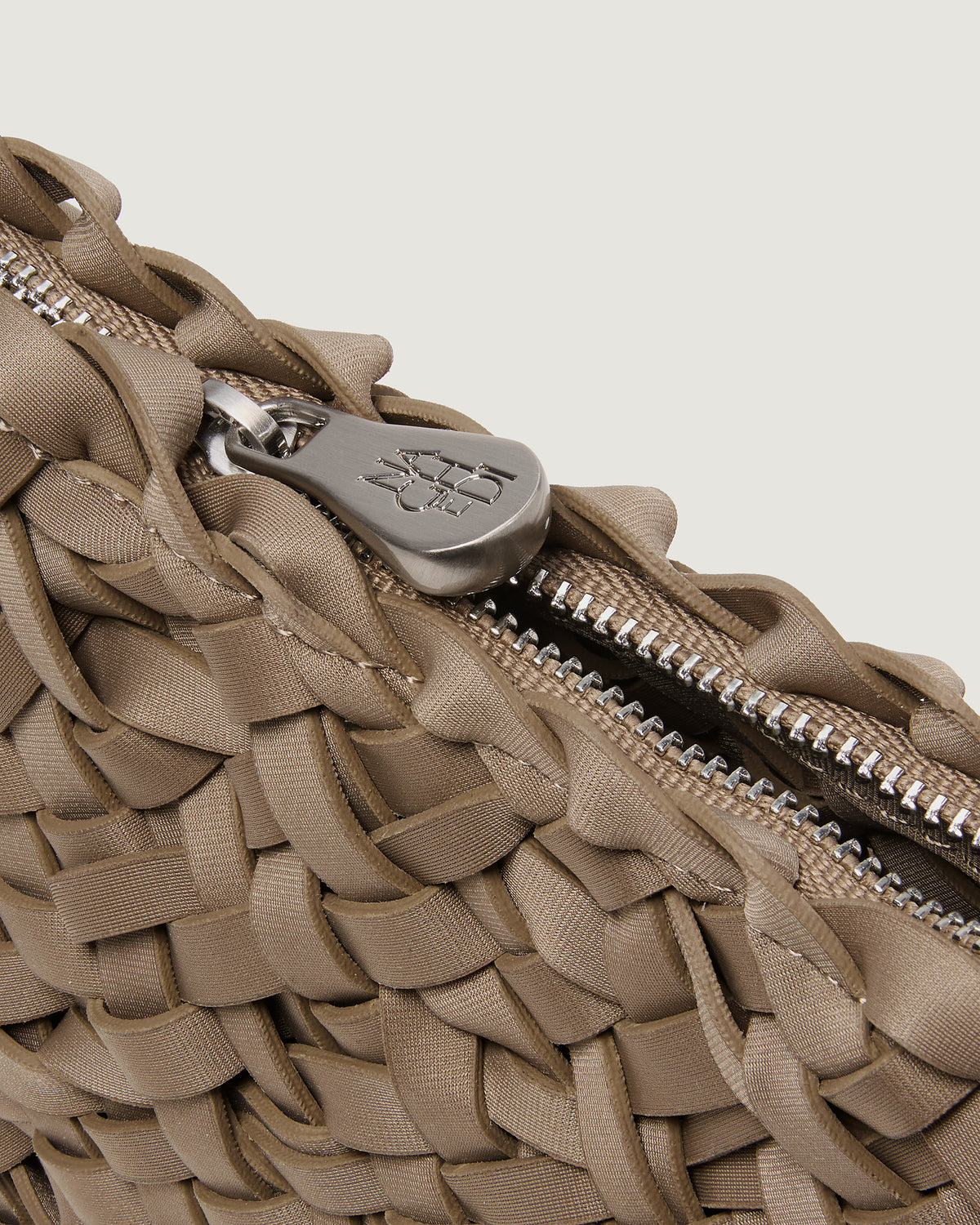 Close up of handwoven neoprene crossbody bag with silver zipper in cool taupe color.