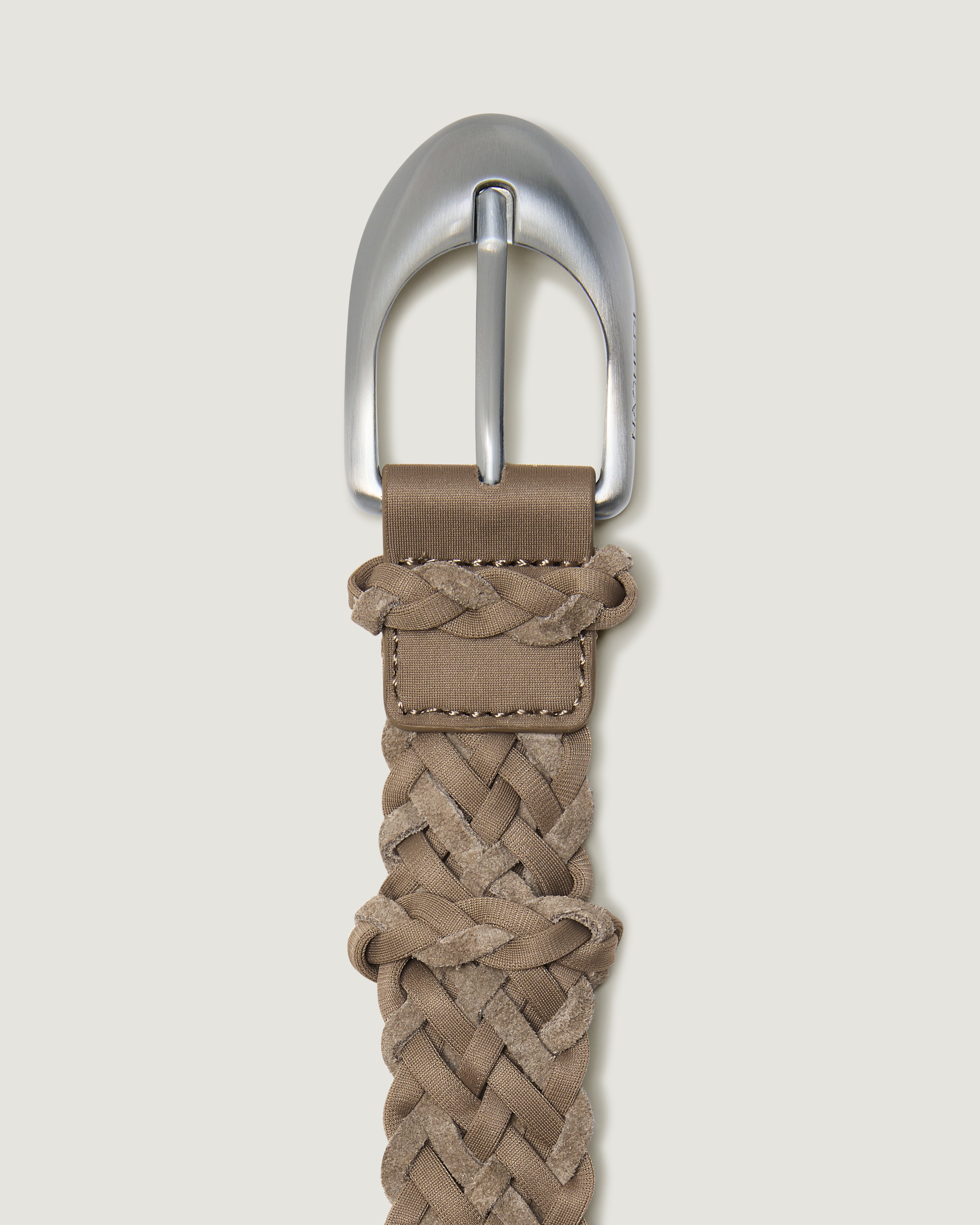 A close-up of a handwoven cool taupe suede and neoprene belt with a polished silver buckle.