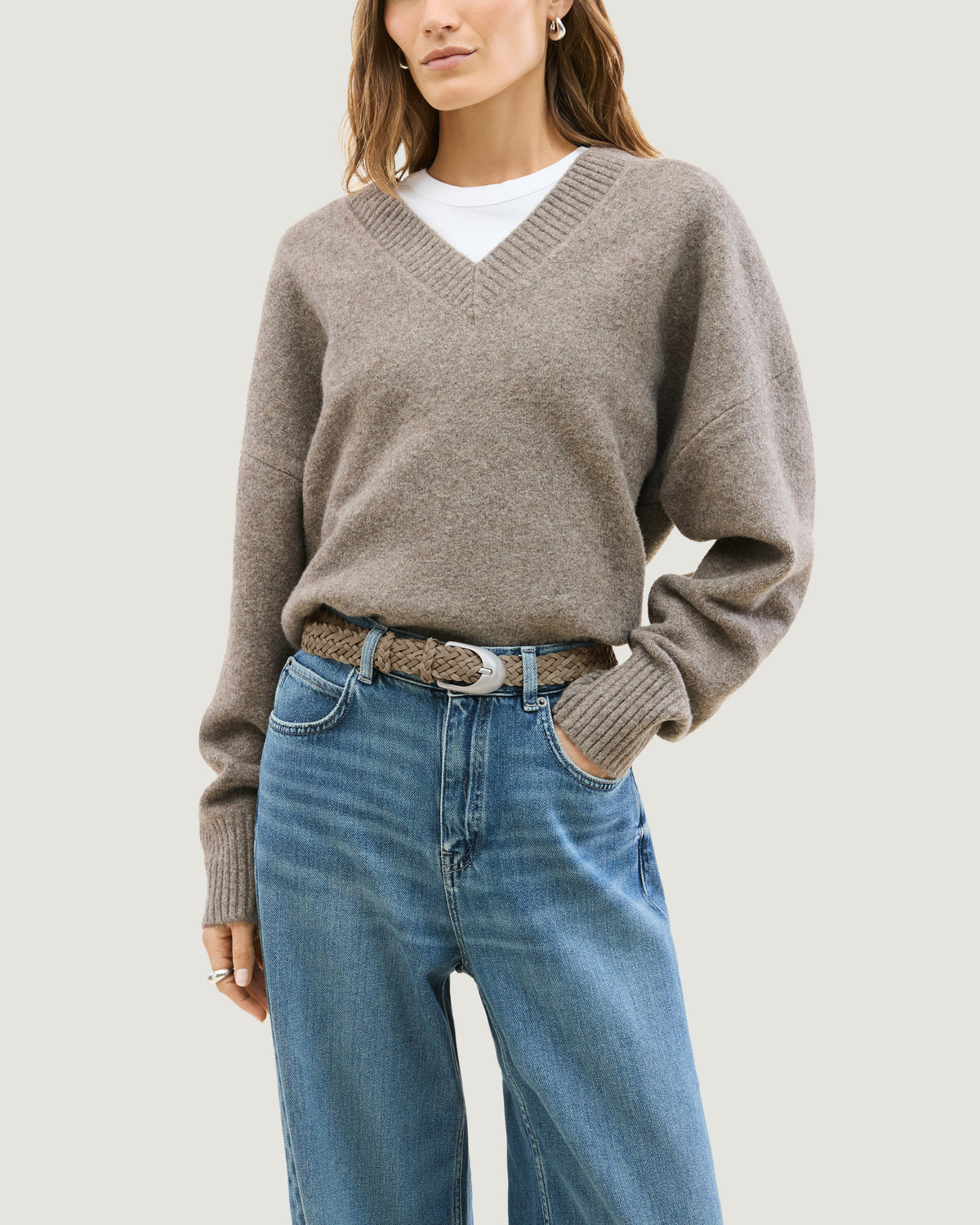 Model wearing a handwoven cool taupe suede and neoprene belt with a polished silver buckle.