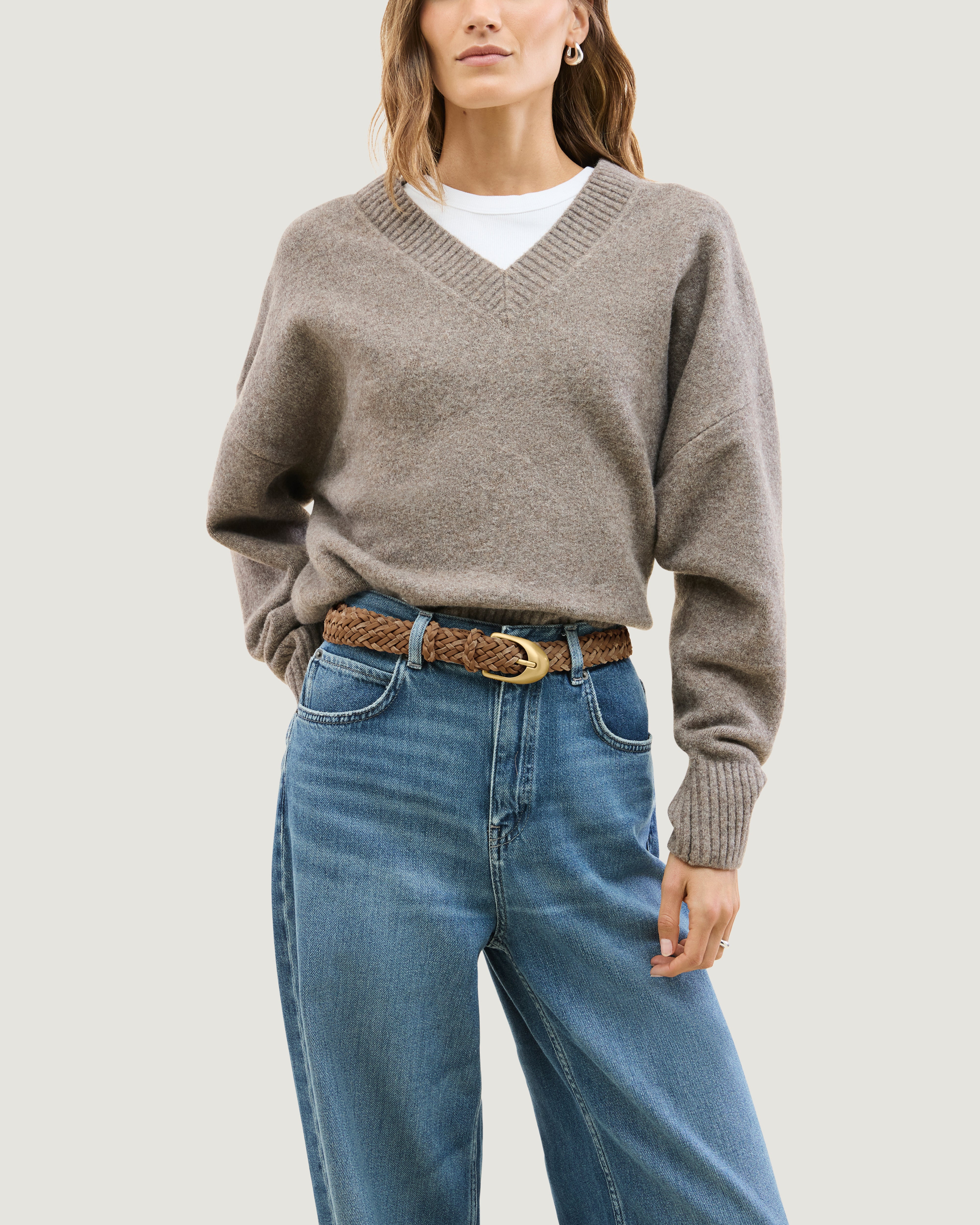 Model wearing a light brown braided neoprene and suede belt with a polished gold buckle.