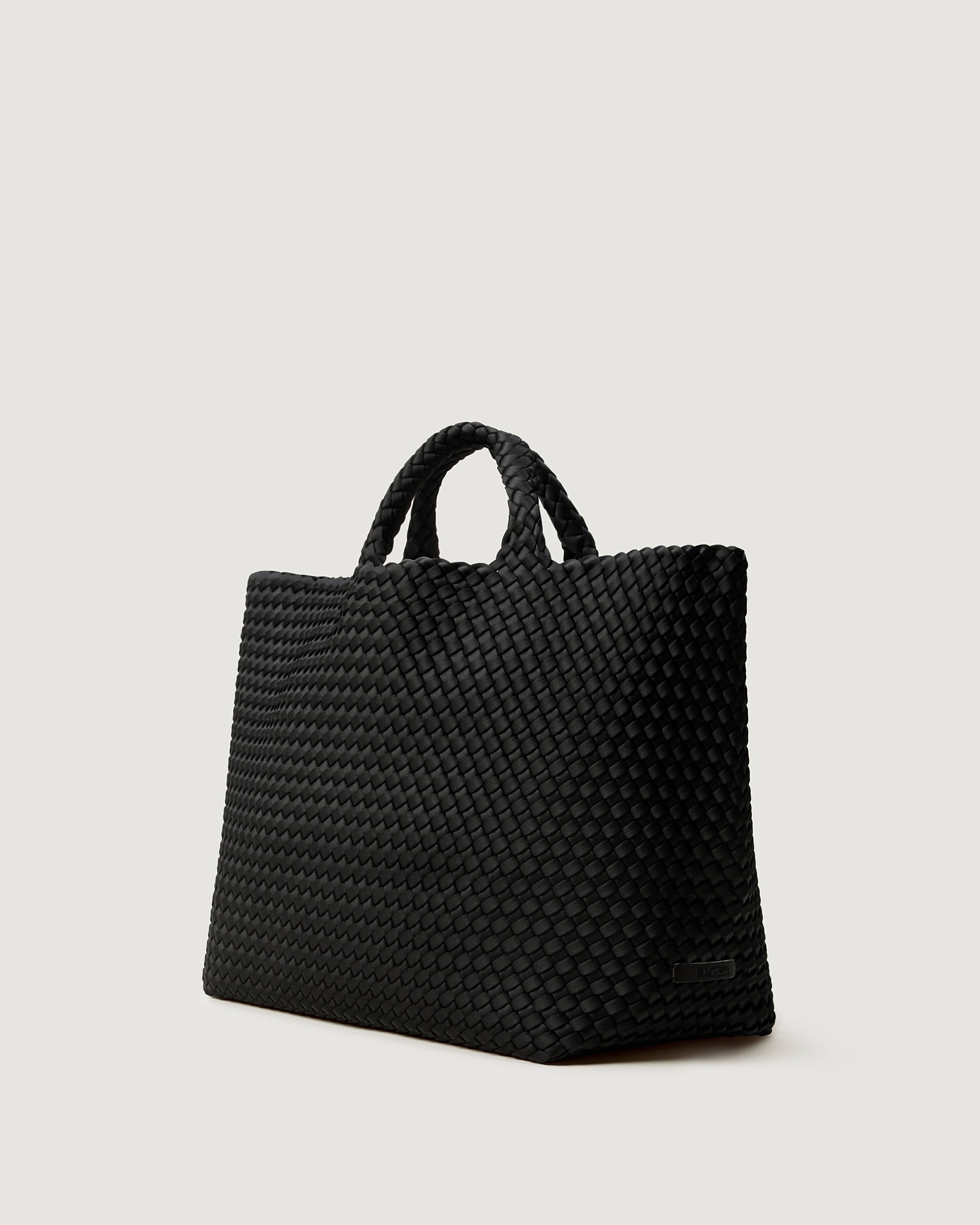St. Barths Tote in Onyx shown from a side angle, highlighting its handwoven neoprene construction and open top.