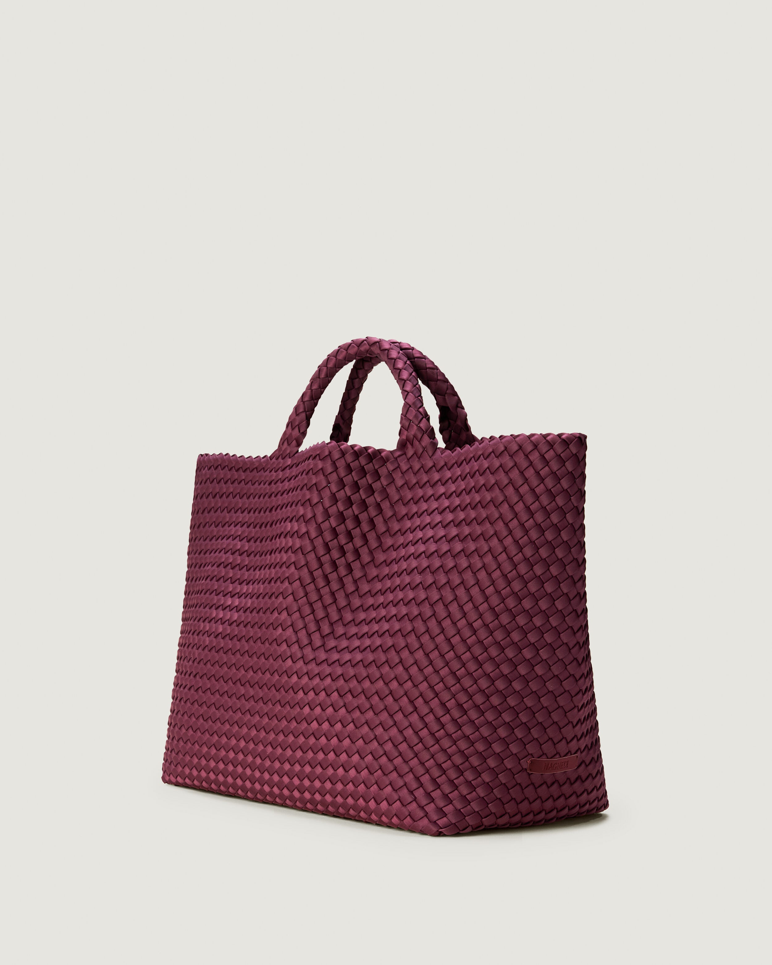 St. Barths Tote in Bordeaux shown from a side angle, highlighting its handwoven neoprene construction and open top.