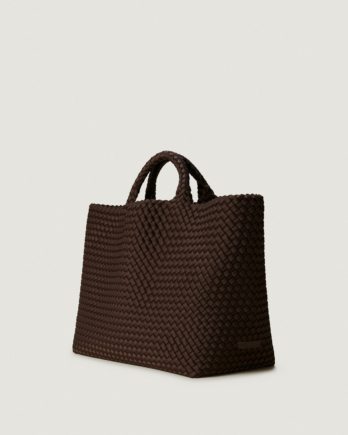 St Barths Tote in Chocolate shown from a side angle, highlighting its handwoven neoprene construction and open top with magnetic snap closure.