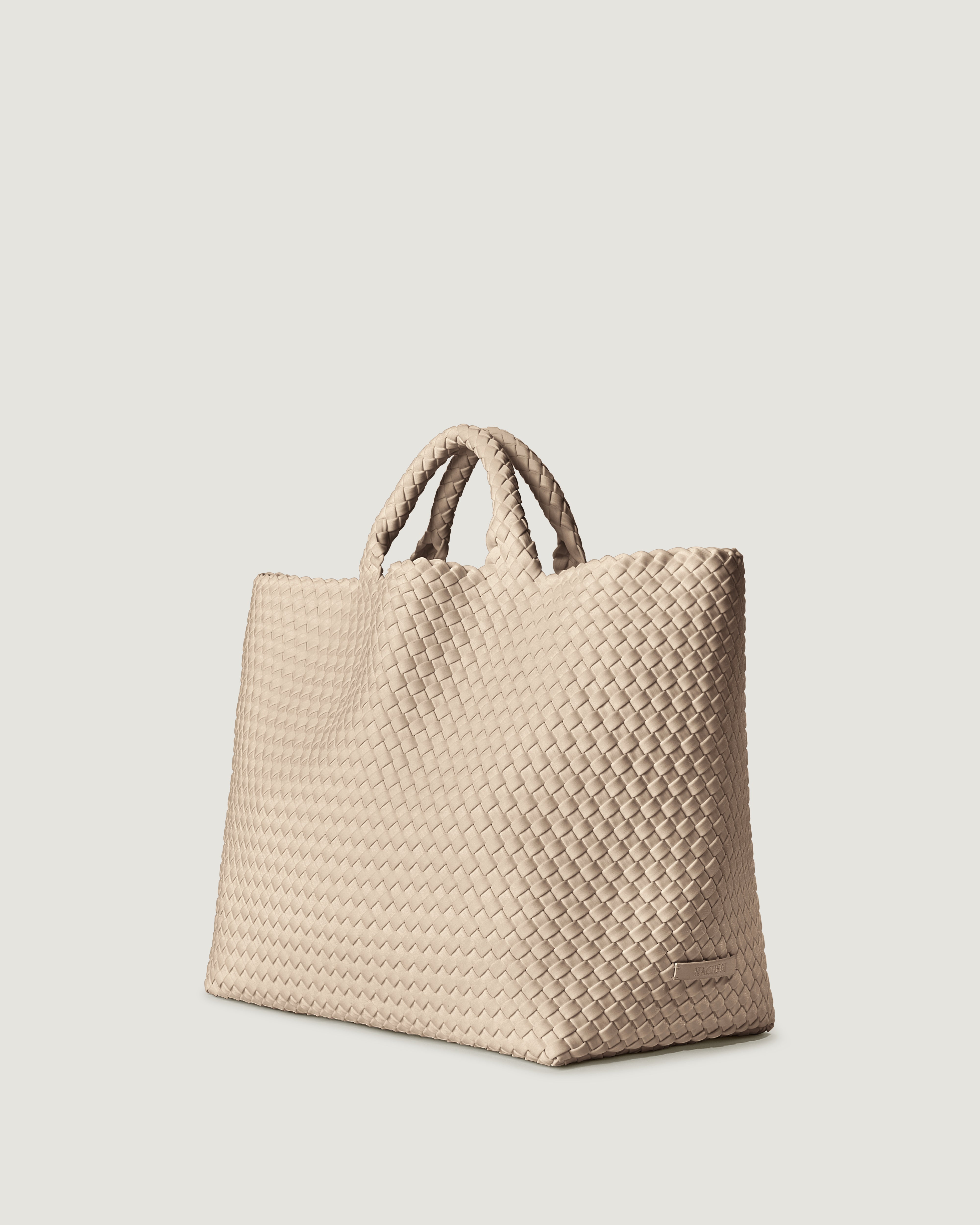 St. Barths Tote in Ecru shown from a side angle, highlighting its handwoven neoprene construction and open top.
